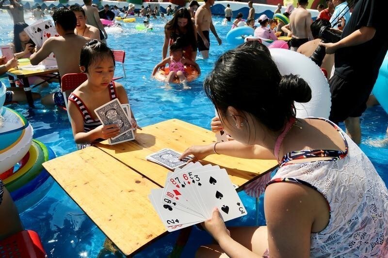People sitting inside a swimming pool play giant cards at a water park on a hot day in Chongqing, China August 19, 2018. Picture taken August 19, 2018. REUTERS/Stringer ATTENTION EDITORS - THIS IMAGE WAS PROVIDED BY A THIRD PARTY. CHINA OUT. TPX IMAGES OF THE DAY - RC1265AA4230