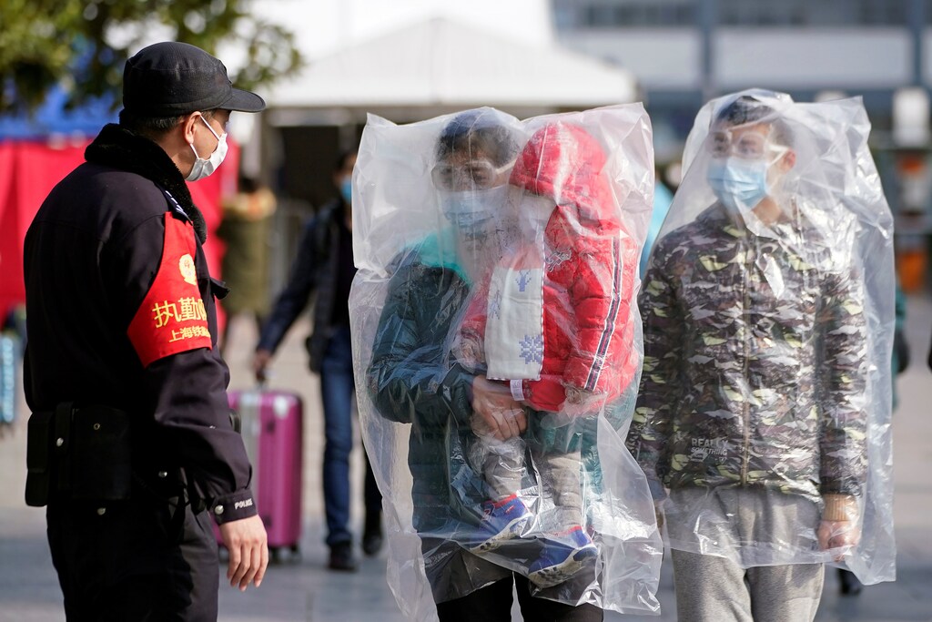 Passengers wearing masks and covered with plastic bags walk outside the Shanghai railway station in Shanghai, China, as the country is hit by an outbreak of a new coronavirus, February 9, 2020. REUTERS/Aly Song - RC21XE9AYSOF