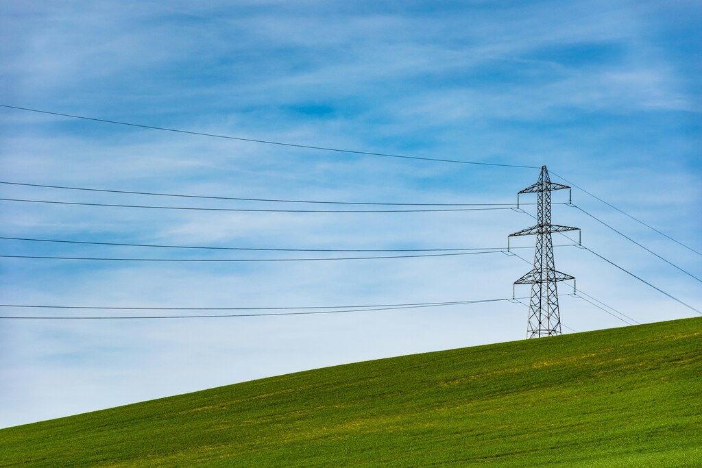 Electricity pylon in the distance on top of a field: Technological development could help overcome the barriers to industrial electrification.