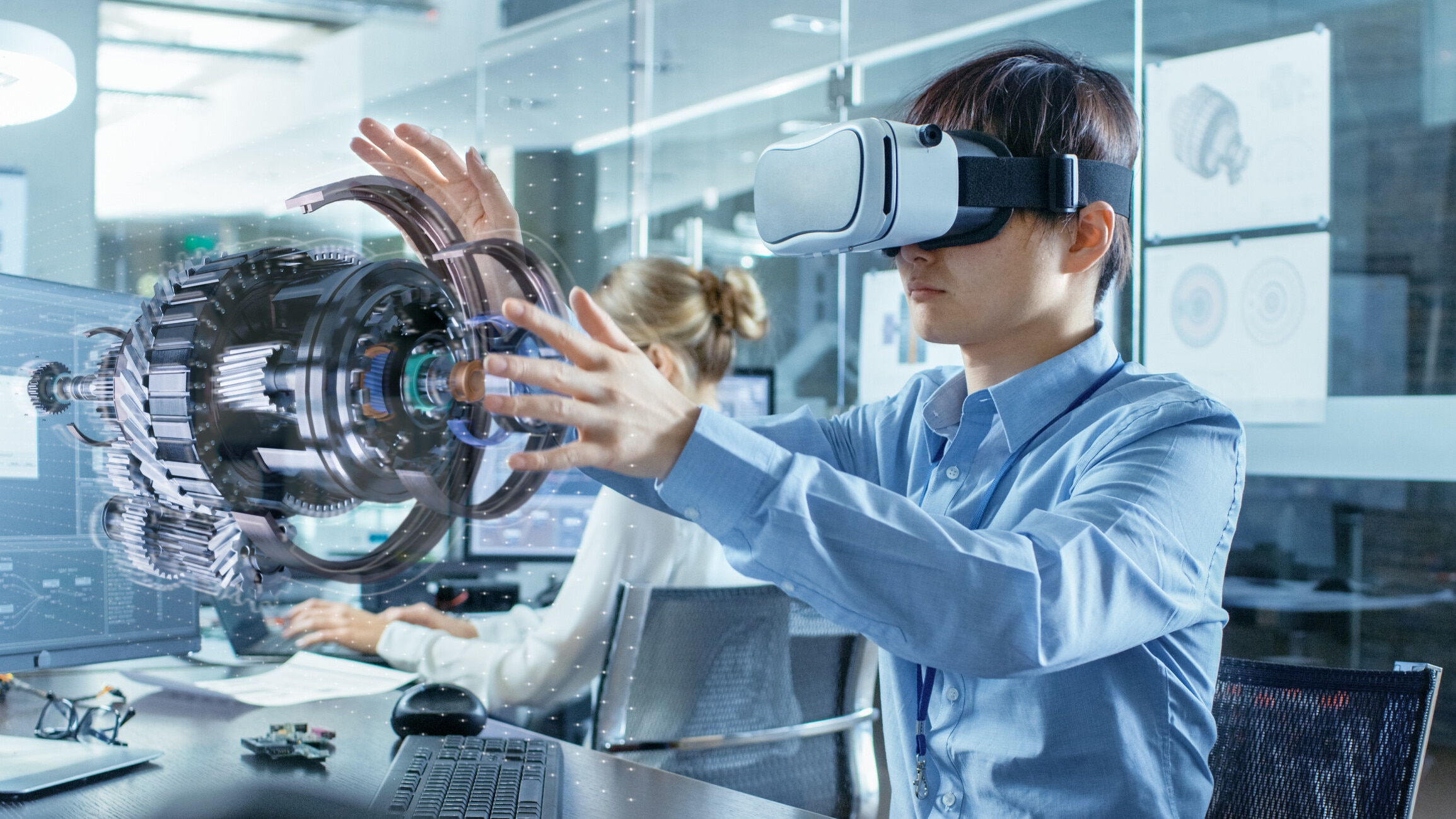 Computer Science Engineer wearing Virtual Reality Headset Works with 3D Model Hologram Visualization, Makes Gestures. In the Background Engineering Bureau with Busy Coworkers. Future of jobs, entrepreneurs