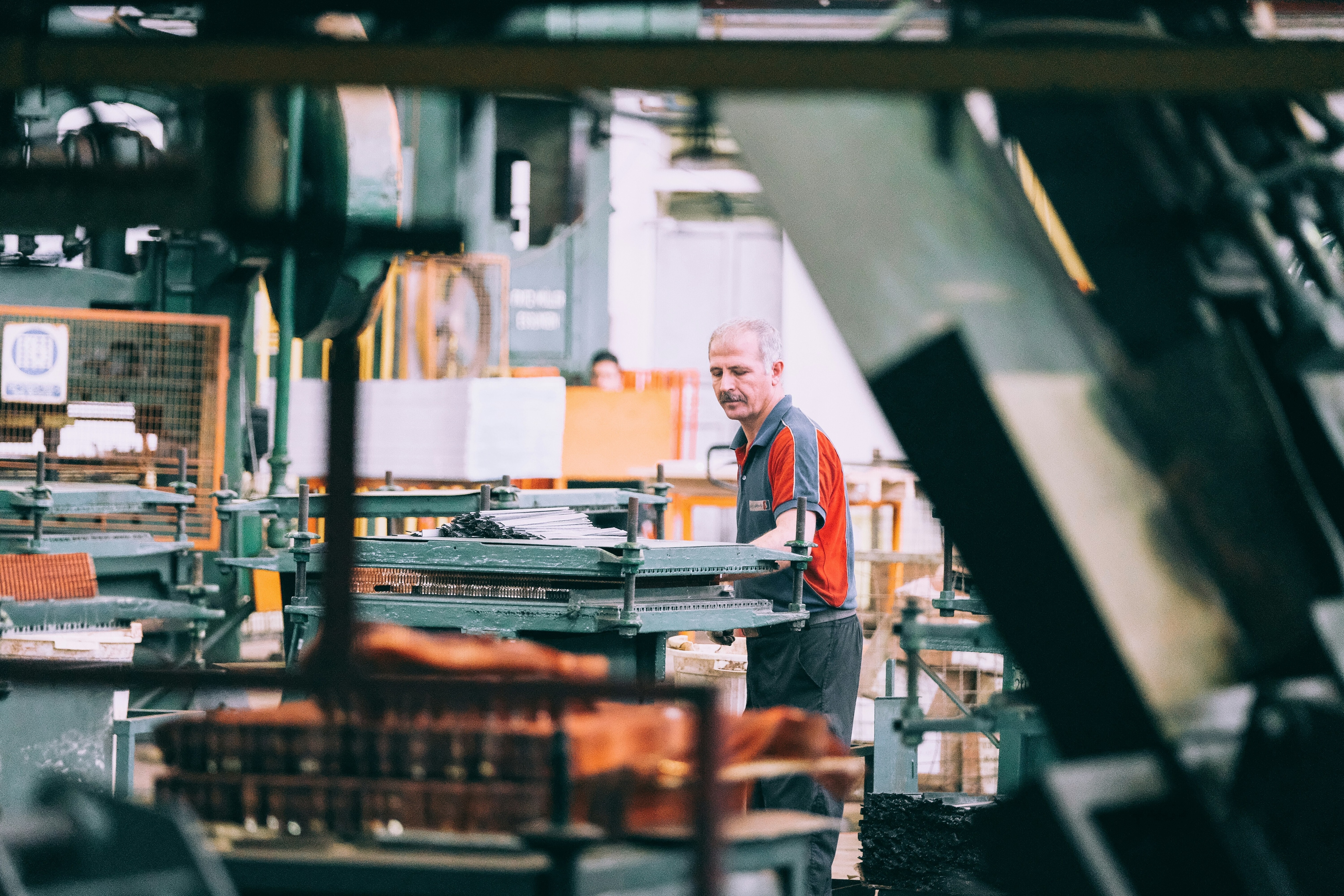A man in a t-shirt is operating machinery in a factory: The real measure of success for advanced manufacturing is how quickly learning can move between sites