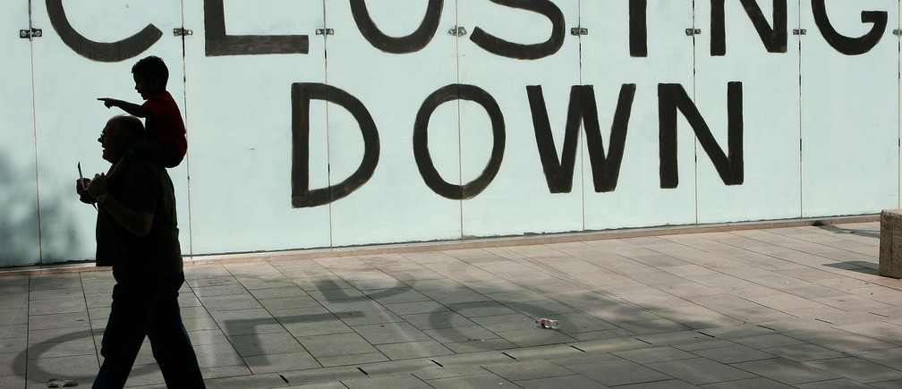 Shoppers walk past a closing down sign in a shop window in Cardiff, Wales, September 9 , 2009. REUTERS/Phil Noble (BRITAIN BUSINESS EMPLOYMENT) - LM1E5991FVZ01