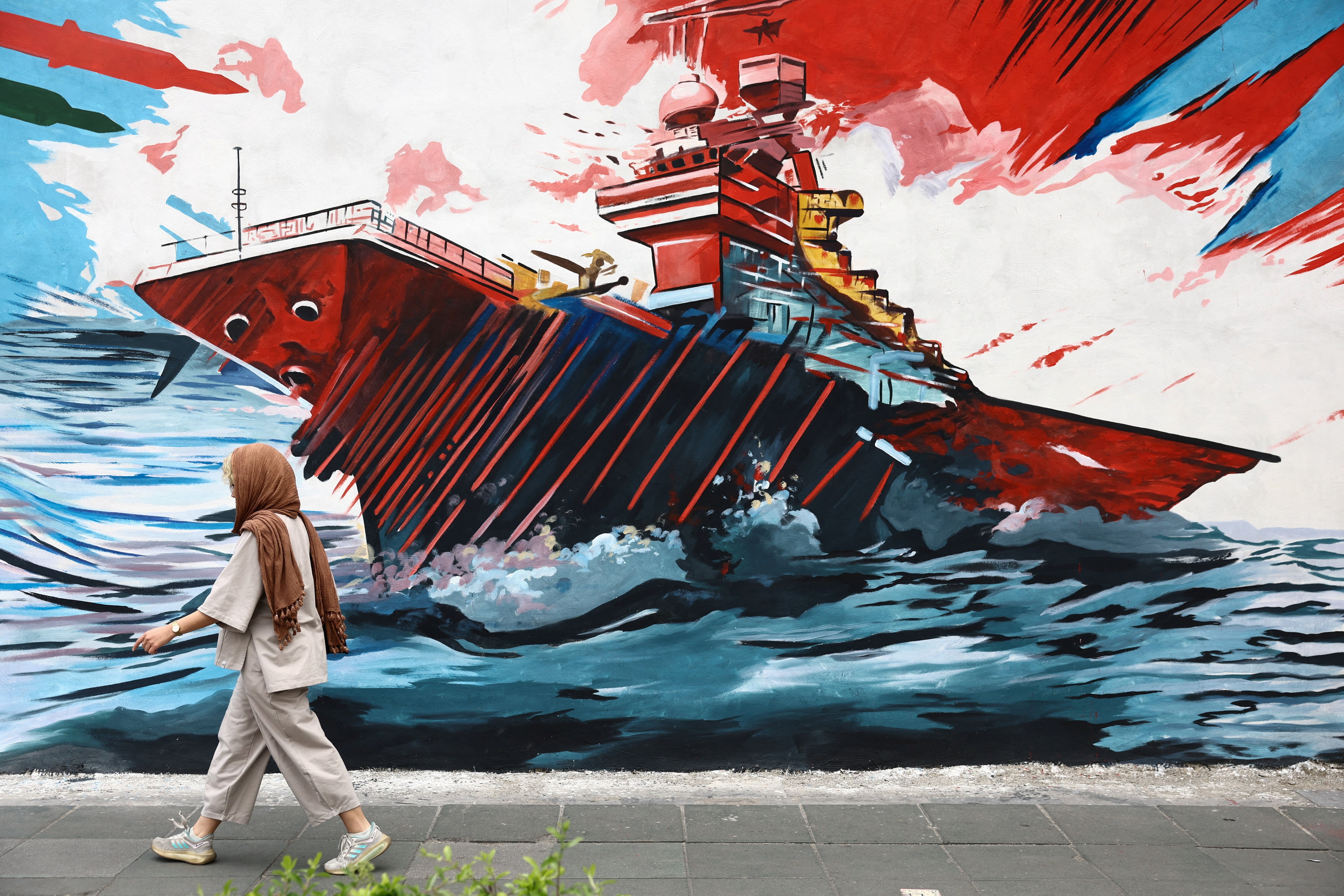 A woman walks next to an anti-U.S. mural on a street in Tehran, Iran, April 12, 2026. Majid Asgaripour/WANA (West Asia News Agency) via REUTERS ATTENTION EDITORS - THIS PICTURE WAS PROVIDED BY A THIRD PARTY.