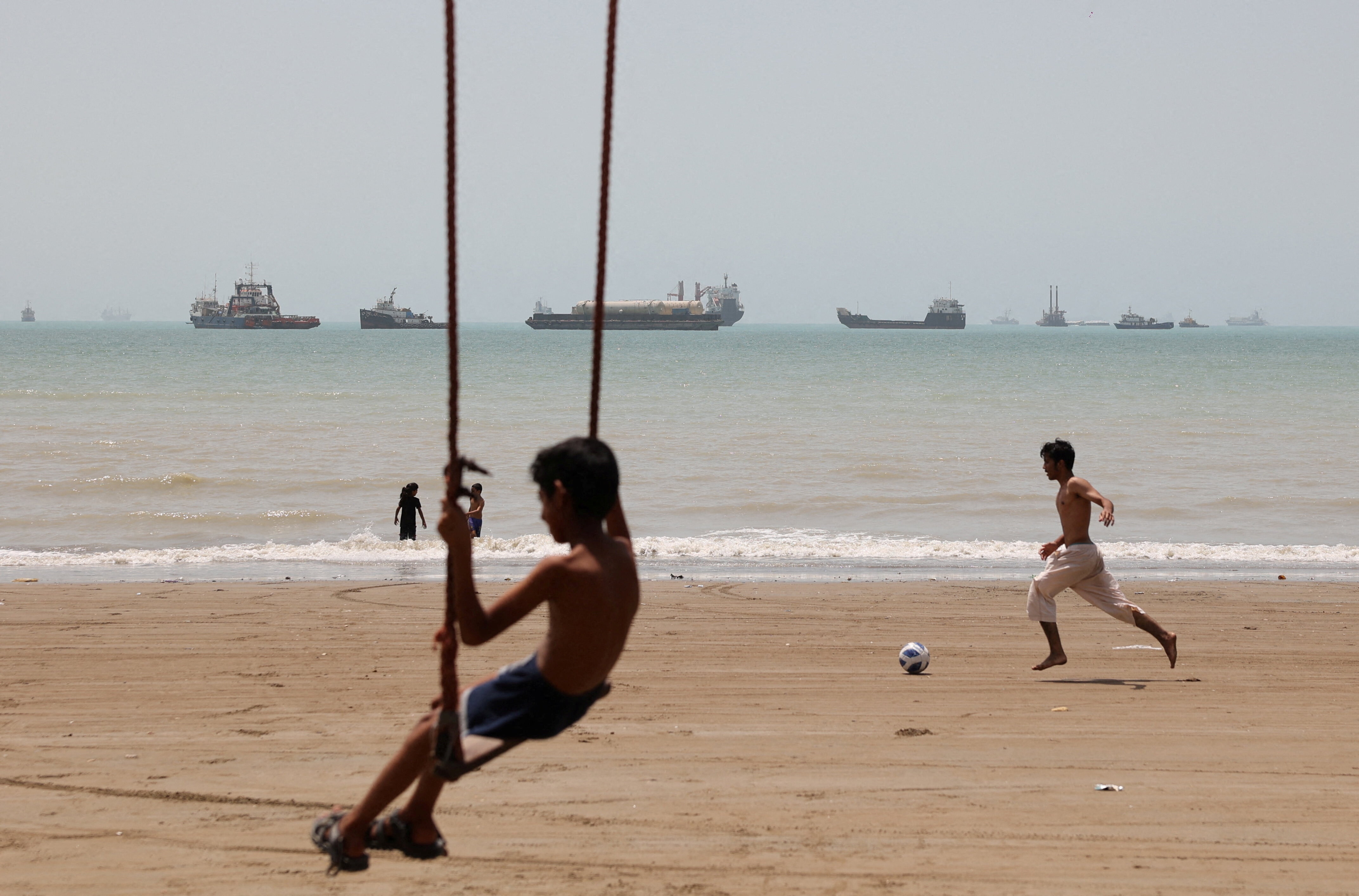 A child plays at the beach, with vessels in the Strait of Hormuz visible near the beach of Bandar Abbas, Iran, May 21, 2026. Majid Asgaripour/WANA (West Asia News Agency) via REUTERS ATTENTION EDITORS - THIS PICTURE WAS PROVIDED BY A THIRD PARTY     TPX IMAGES OF THE DAY