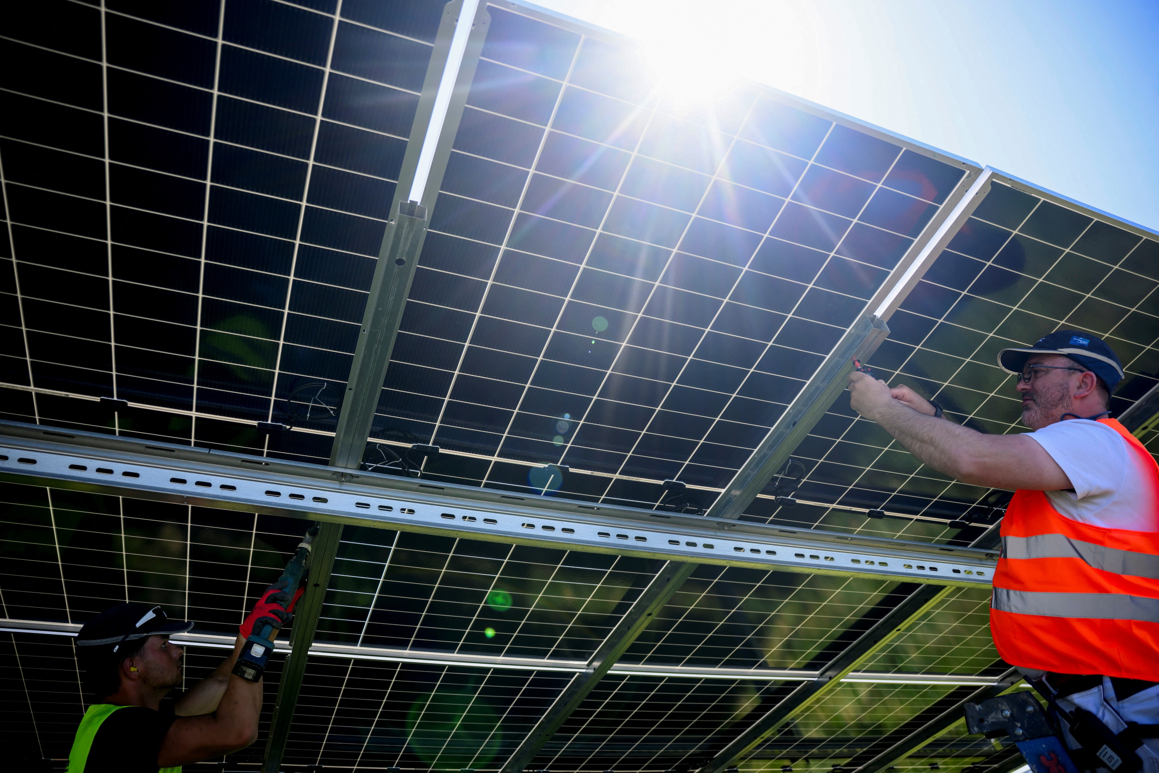 Workers set up new solar panels at a site under construction in a sign of changing energy markets.