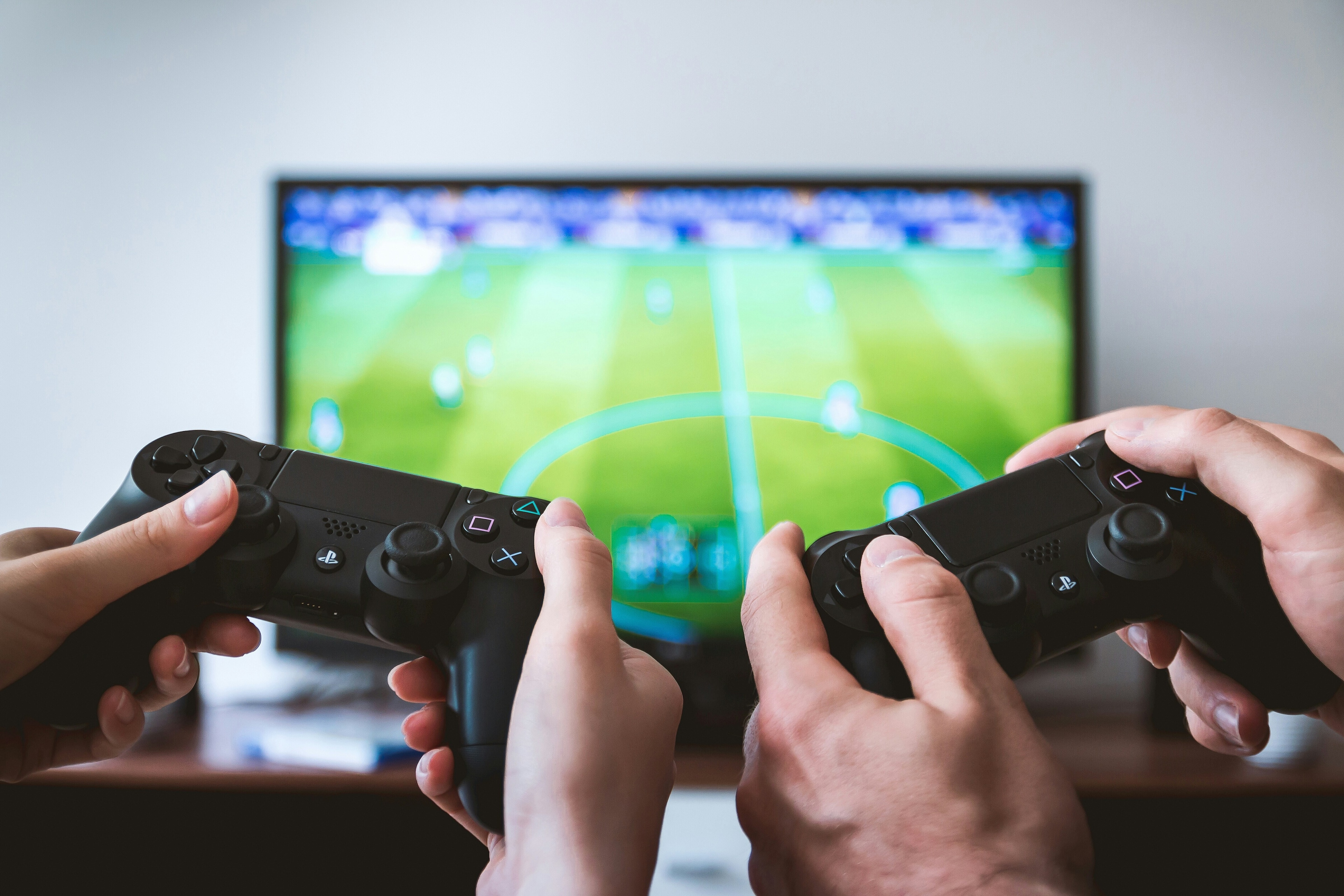 People using gaming consoles to play a football game
