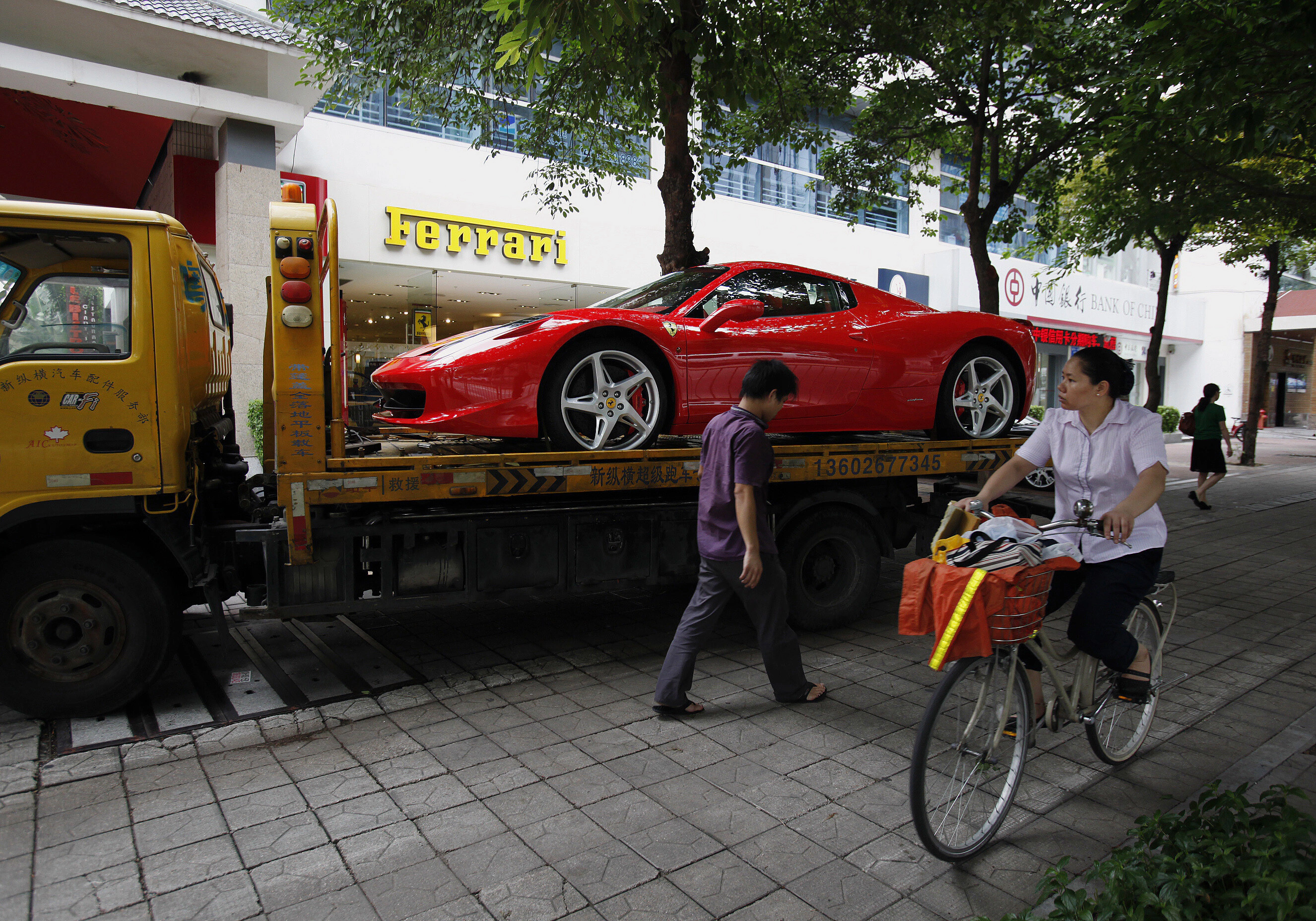 Un Ferrari 458 Spider es cargado en un camión tras ser comprado por un joven chino en un concesionario de Shenzhen, en esta foto de archivo del 28 de mayo de 2012. Las marcas de lujo que apuestan por una recuperación del consumo en China para impulsar sus ventas podrían llevarse una sorpresa desagradable: la débil demanda en el segundo mayor mercado de lujo del mundo podría extenderse más allá de la desaceleración económica, a medida que Beijing reprime el consumo ostentoso. El gobierno impuso una norma de “estilo de trabajo frugal” para sus funcionarios, que entra en vigor el 1 de octubre de 2012, y que les prohíbe gastar dinero público en banquetes lujosos o autos costosos, así como aceptar regalos de alto valor. REUTERS/Bobby Yip/Archivo (CHINA – Etiquetas: SOCIEDAD NEGOCIOS TRANSPORTE)