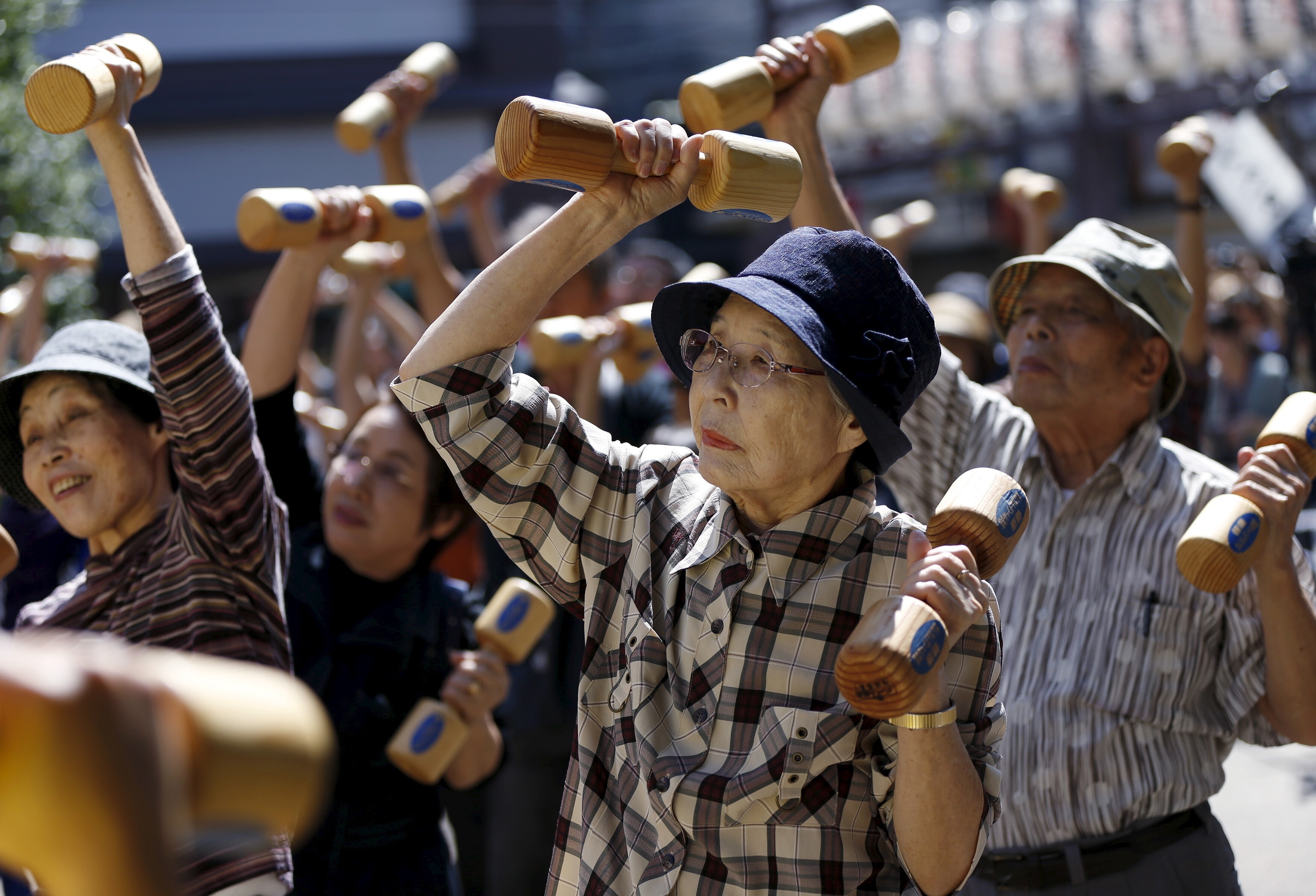 Elderly and middle-age people exercise with wooden dumbbells during a longevity promotion event to mark Japan's "Respect for the Aged Day" at a temple in Tokyo's Sugamo district, an area popular among the Japanese elderly, September 21, 2015. 