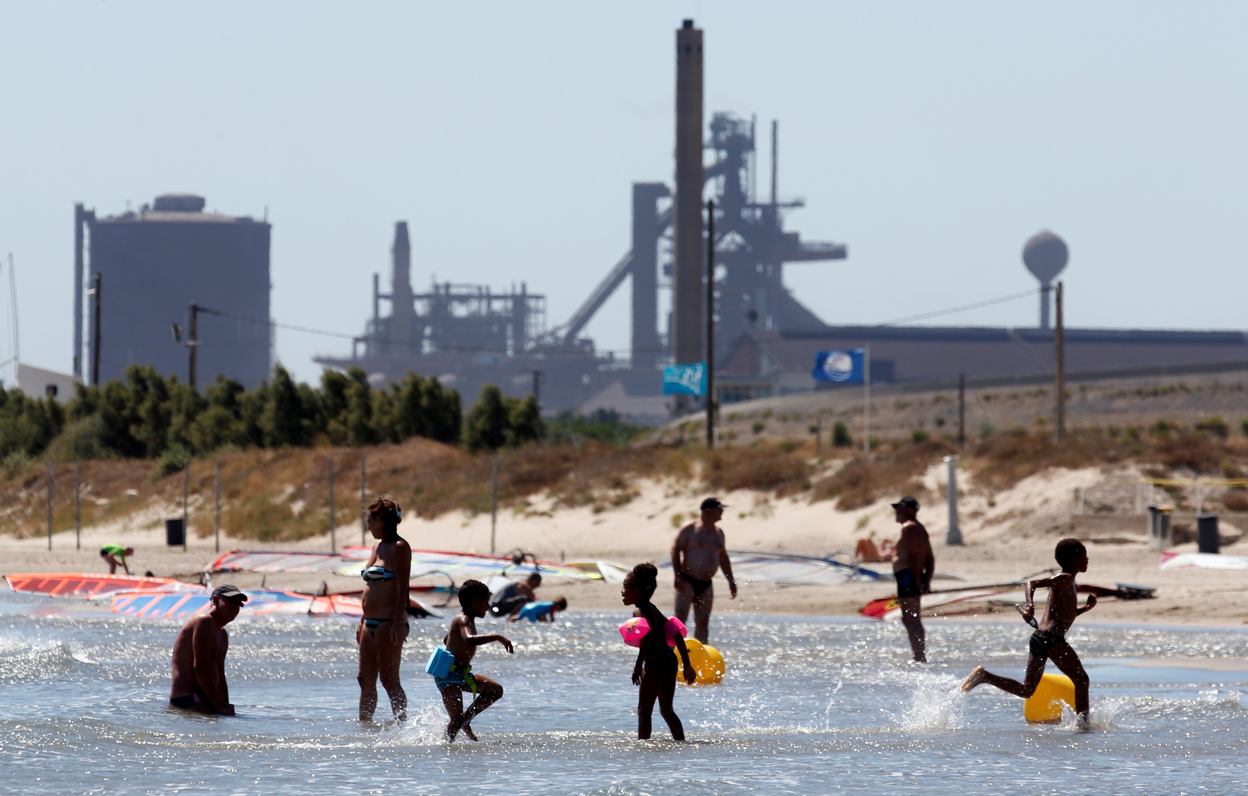People bath to cool off on a Mediterranean beach near Marseille's Fos-Berre industrial cluster. 