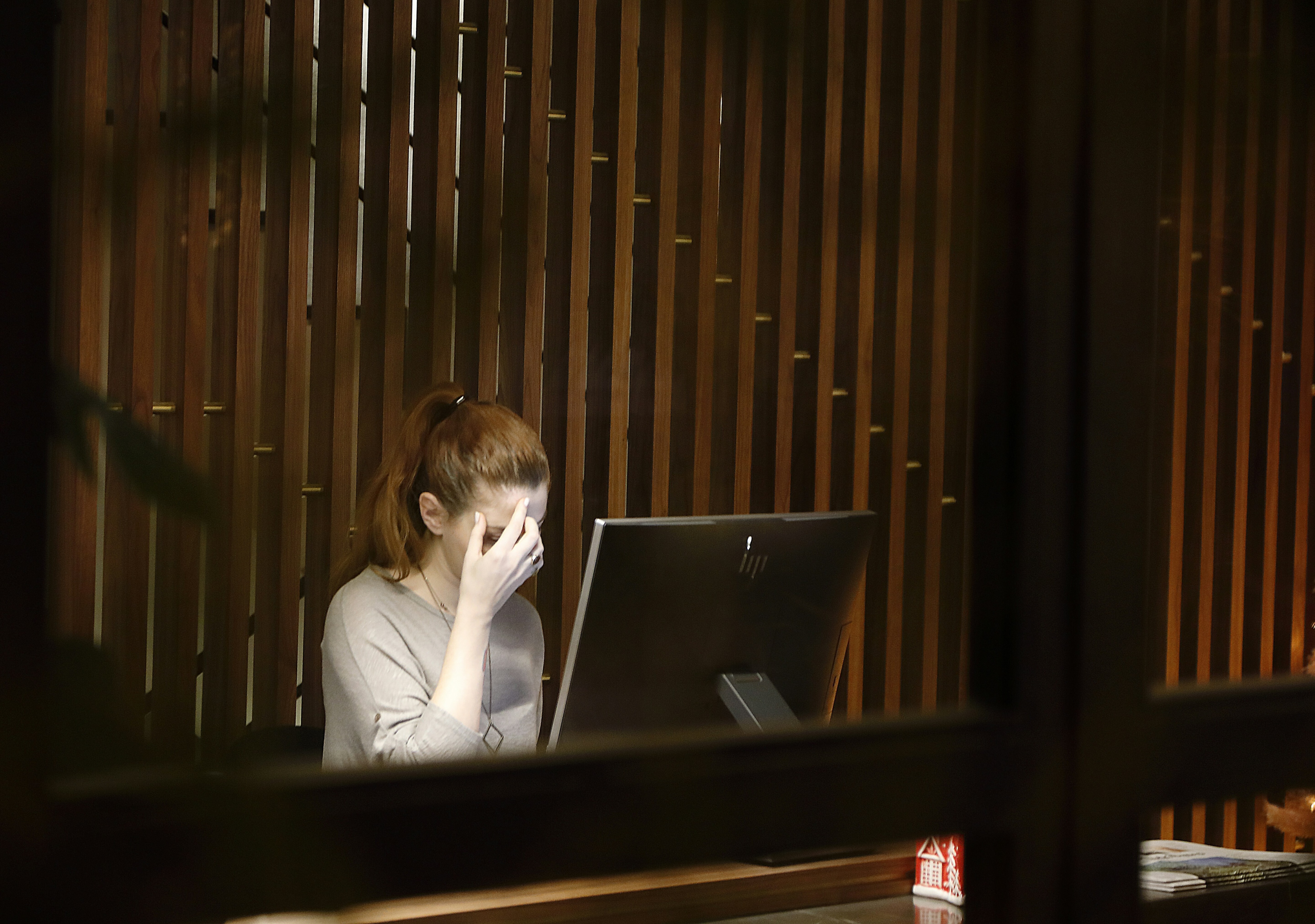 A woman hold her hand up to her head while working at a computer.
