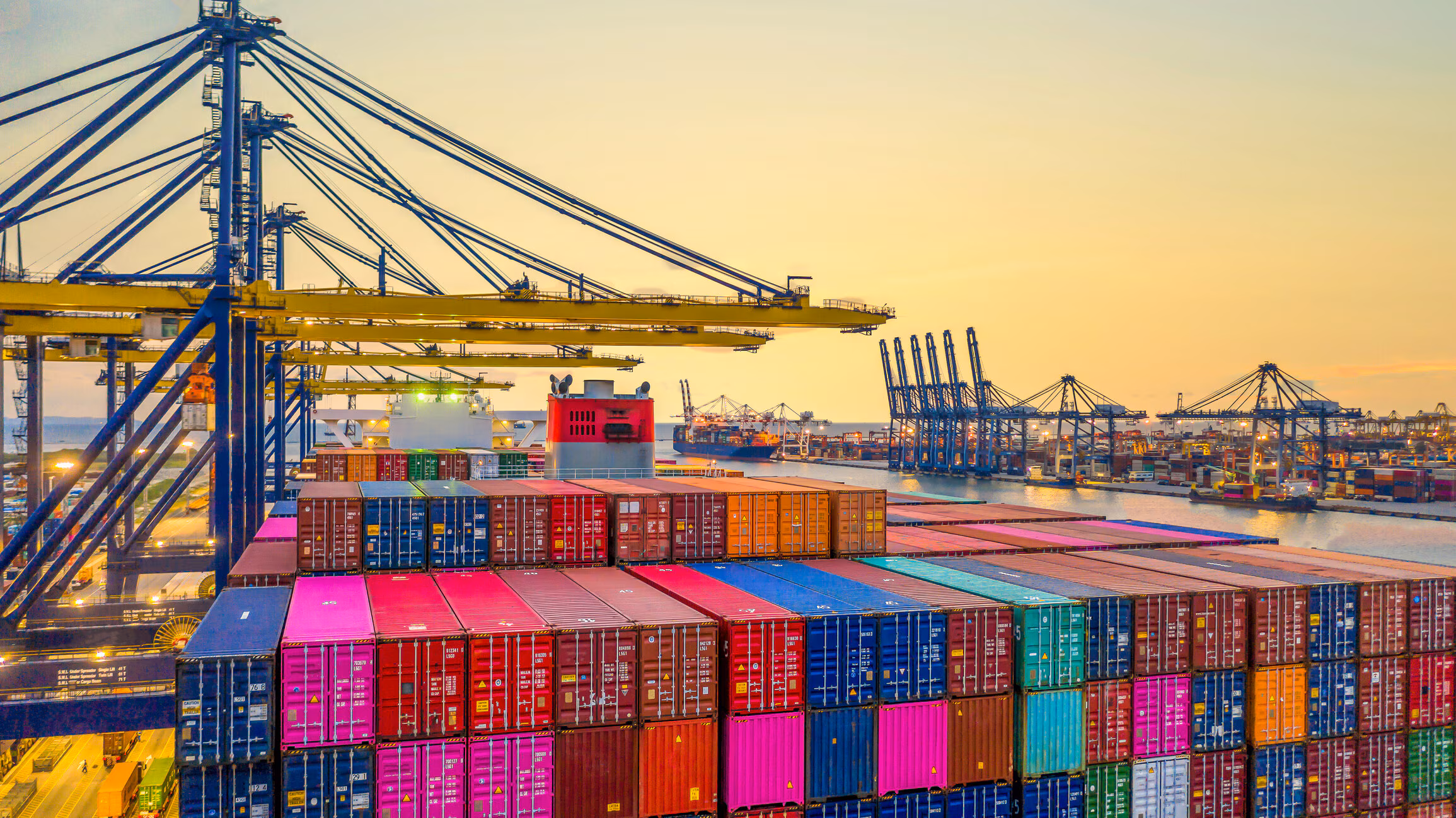 Geoeconomía: Vista de un buque portacontenedores en un puerto industrial, representando la logística del comercio global.