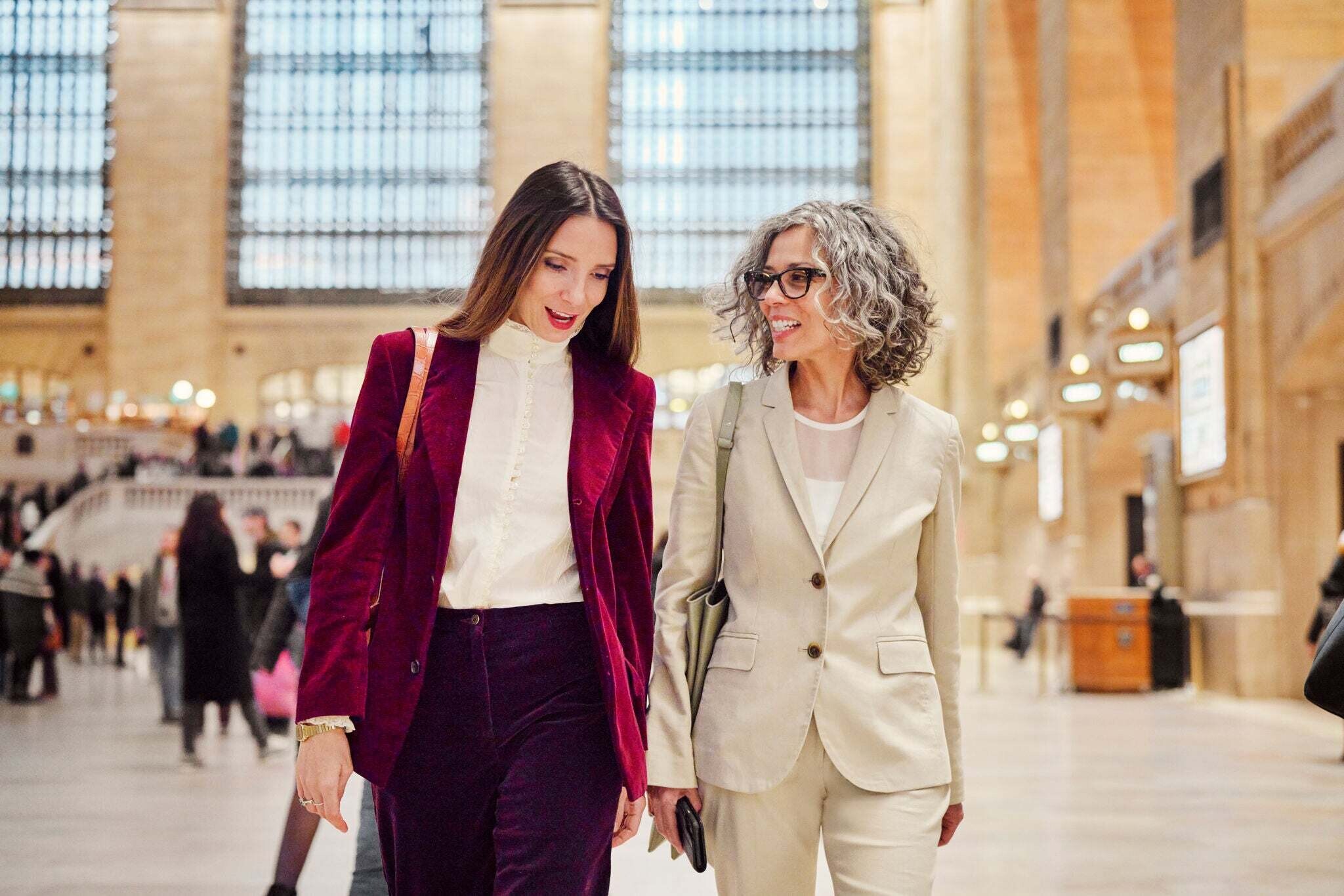 Two women in suits walking, talking and smiling: Women's leadership is lacking, especially in AI and entrepreneurship