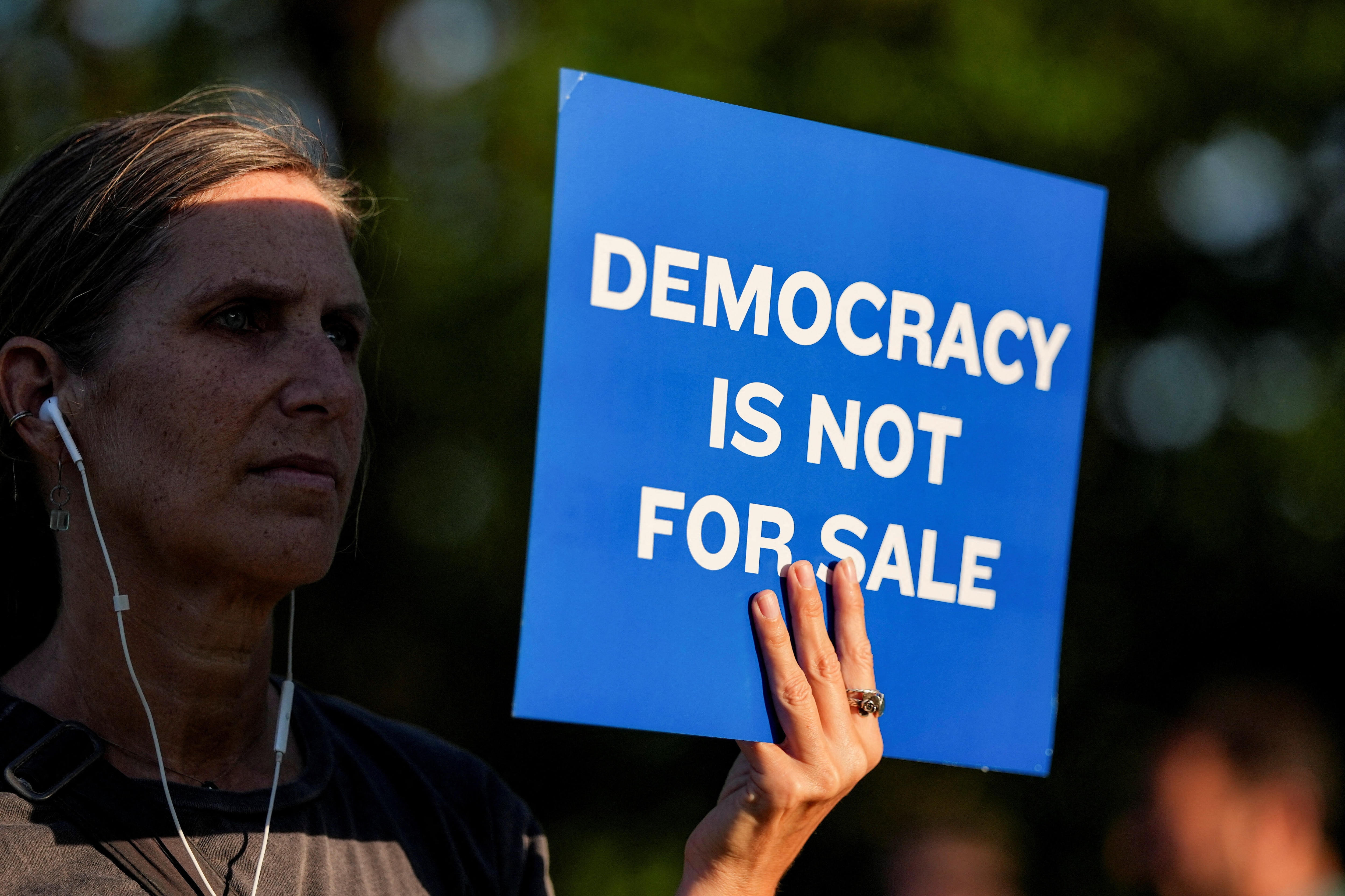 A woman holds a sign during a protest outside the Donald J. Trump Institute of Peace in Washington, D.C., U.S., April 23, 2026. REUTERS/Ken Cedeno