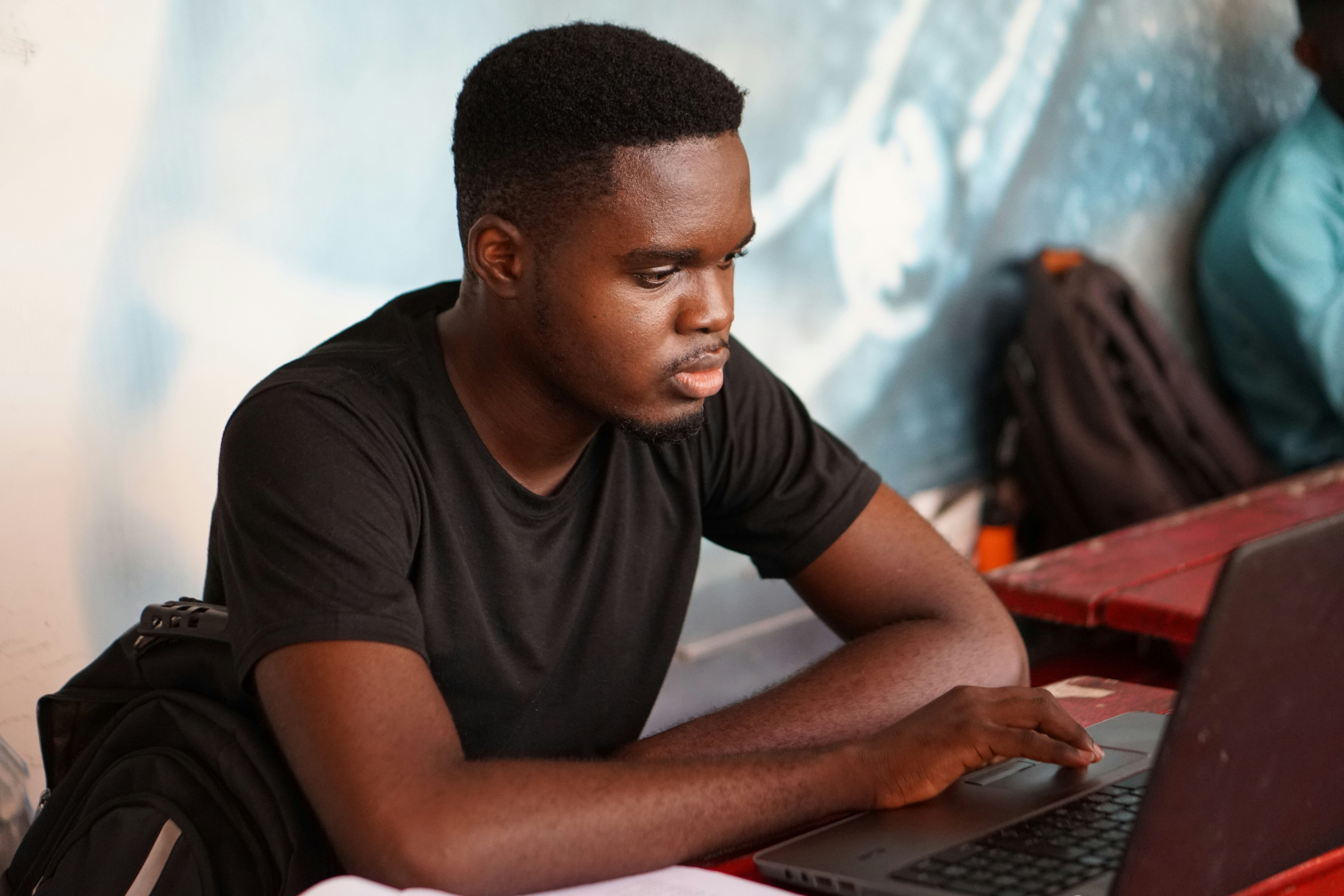 A close up of a young man on his laptop in a communal area: Skills development should be considered as a continuum otherwise we risk fragmented pathways to economic sustainability