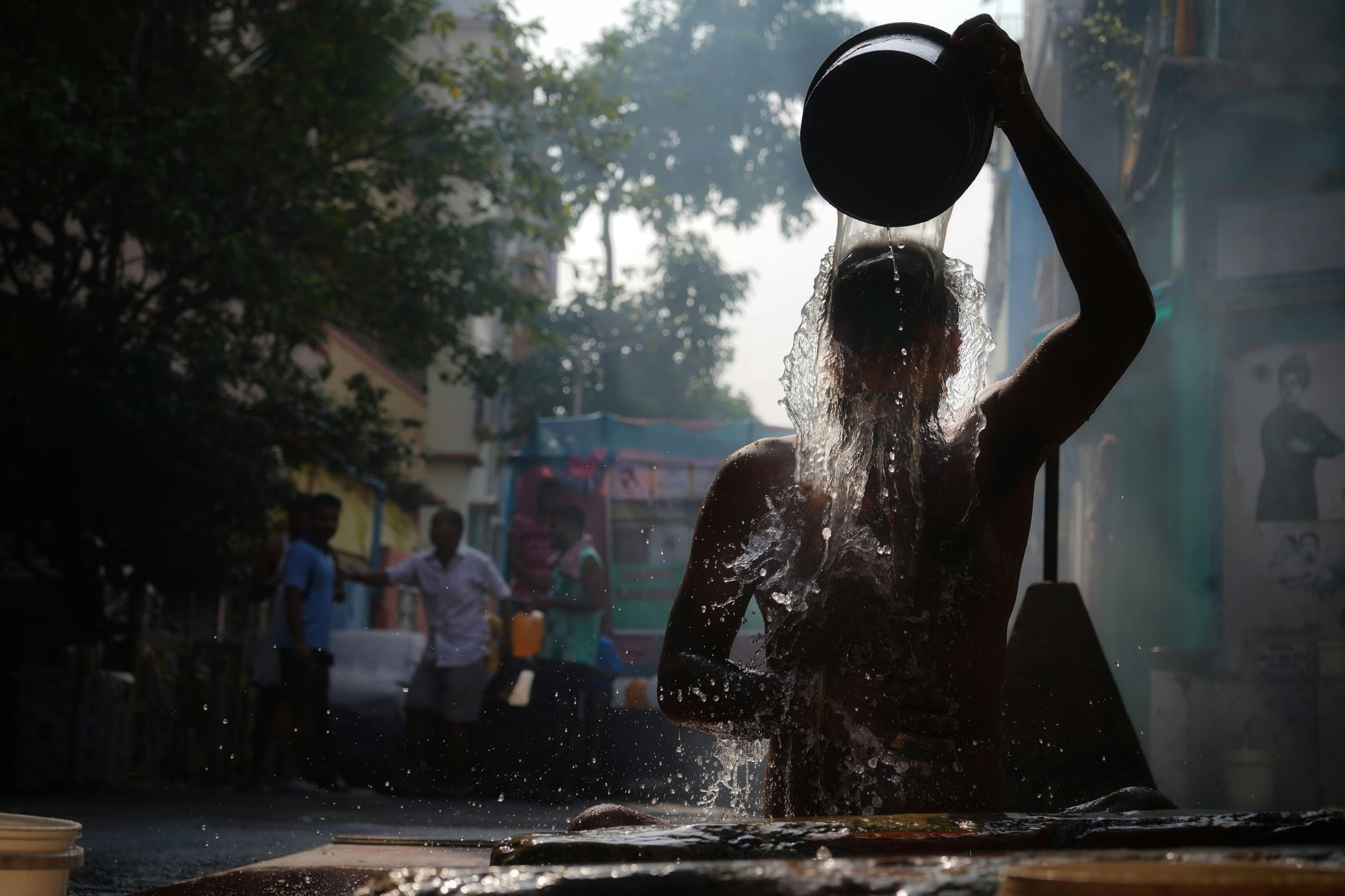 Man pours clean water over his head; India, city; Urban water system