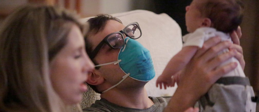 Emergency medicine physician Thomas Krajewski wears a mask as he holds his baby Cal with his wife Genevieve after finishing his shift amid an outbreak of coronavirus disease (COVID-19) in New Orleans, Louisiana, U.S., March 27, 2020. Picture taken March 27, 2020.  REUTERS/Kathleen Flynn     TPX IMAGES OF THE DAY - RC24UF9W8LKC