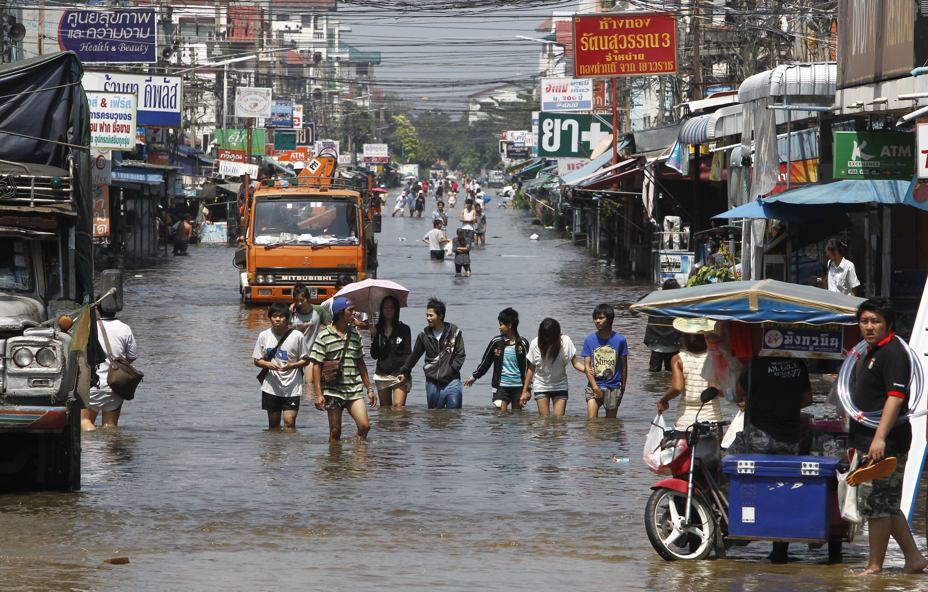 People wade through a flooded street in Pathum Thani province, a suburb of Bangkok, October 19, 2011. Flooding in the north, northeast and centre of the country has killed at least 317 people since July and damaged large areas of farmland in the world's top exporter of rice: Investing in climate adaptation makes sense when considered through water