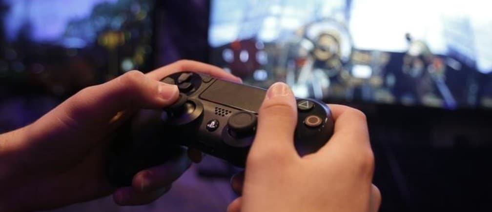 A visitor plays a Playstation 4 at the Sony exhibition stand during the Gamescom 2013 in Cologne August 21, 2013. Sony has had more than one million preorders worldwide for its new PlayStation 4 console, the head of its SCE computer entertainment division said on Tuesday.  Sony has priced the PlayStation 4, its first new console in seven years, $100 lower than the new Xbox One by Microsoft at $399. The Gamescom convention, Europe's largest video games trade fair, runs from August 22 to August 25. REUTERS/Ina Fassbender (GERMANY - Tags: BUSINESS ENTERTAINMENT)