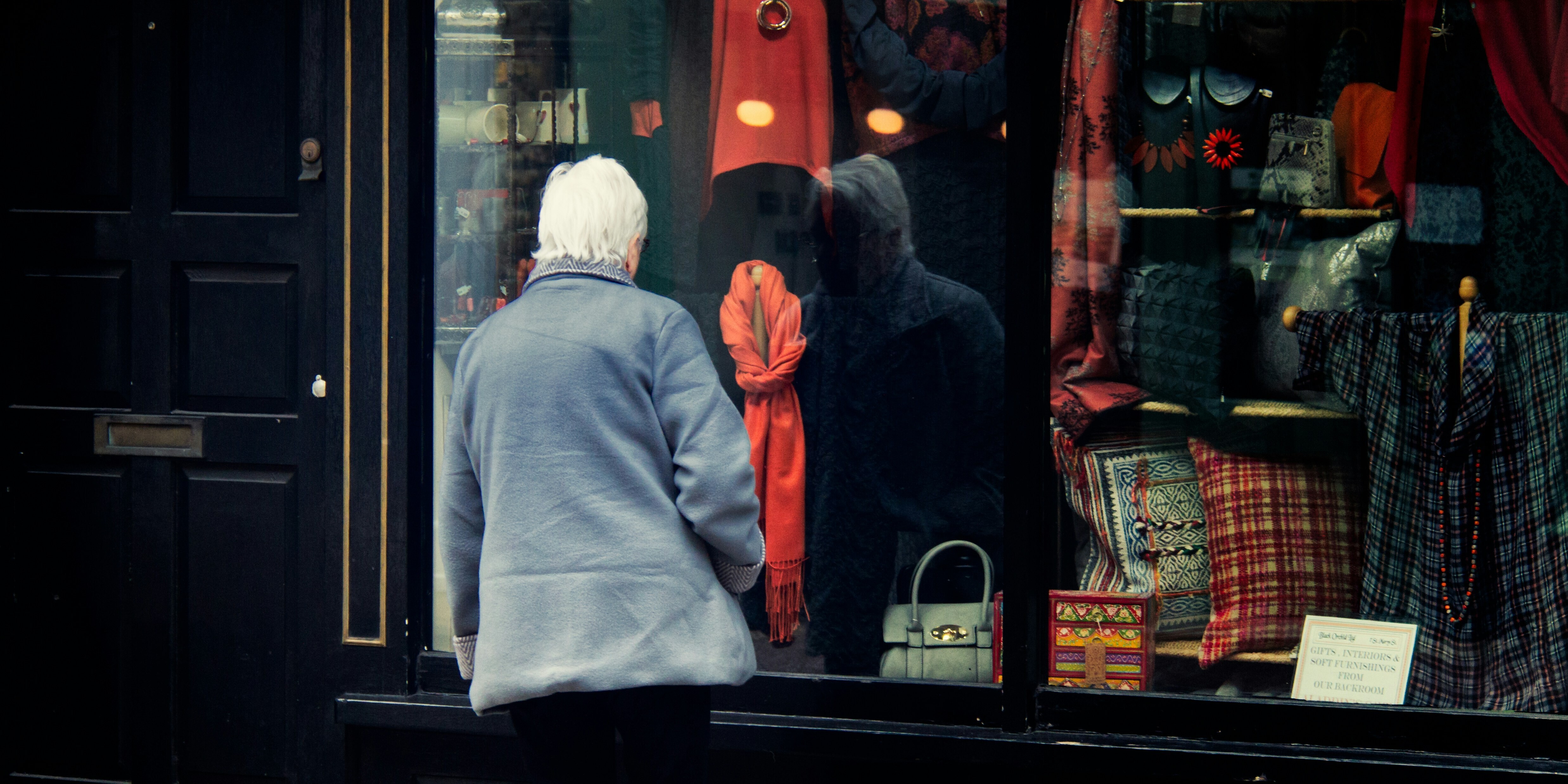 An elderly lady looks in a shop window.