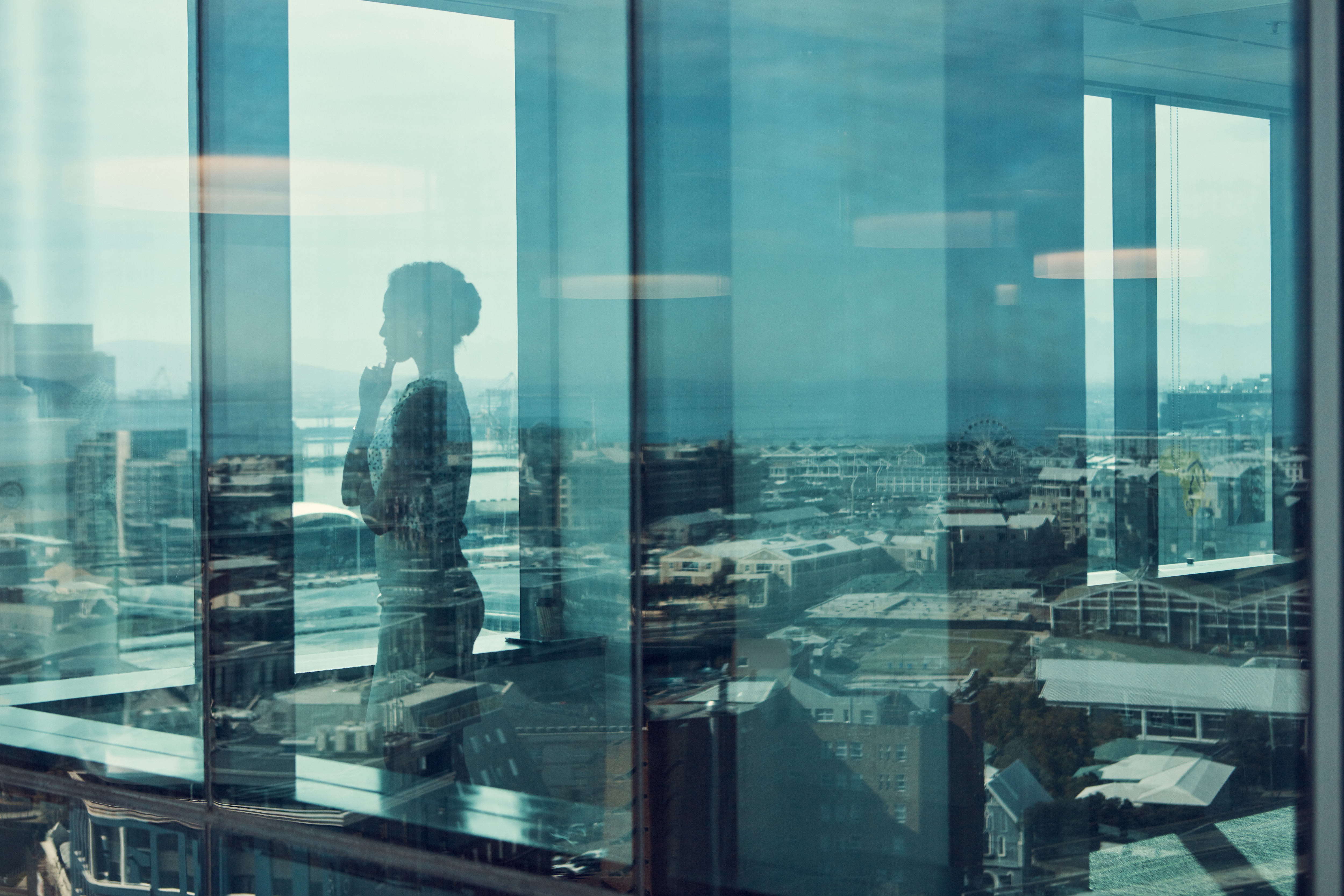 A silhouette reflection of a woman in an office overlooking a city: Gender parity depends on redesigning the leadership machinery