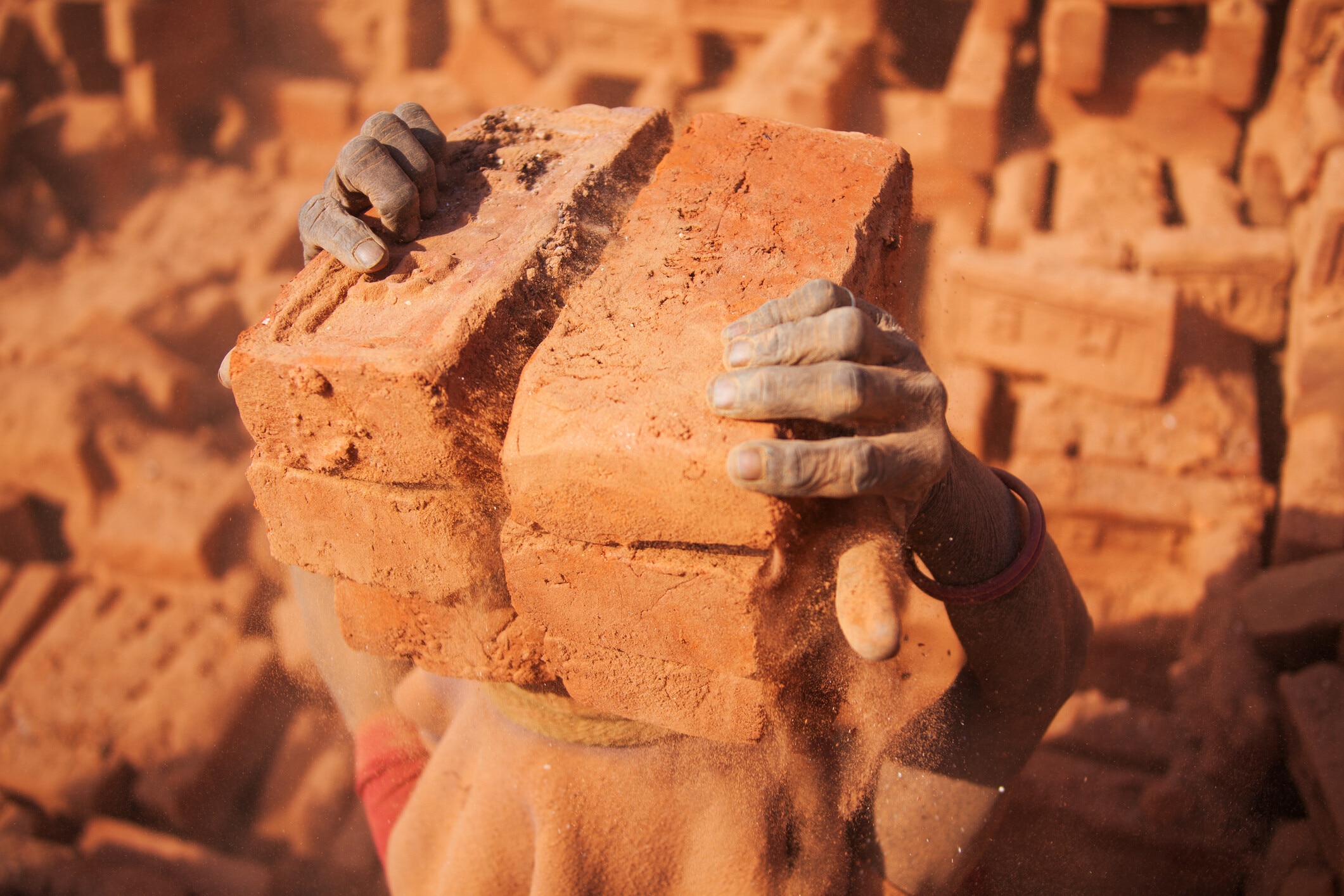 Worker carrying heavy bricks in a kiln, illustrating the harsh reality of forced labour.
