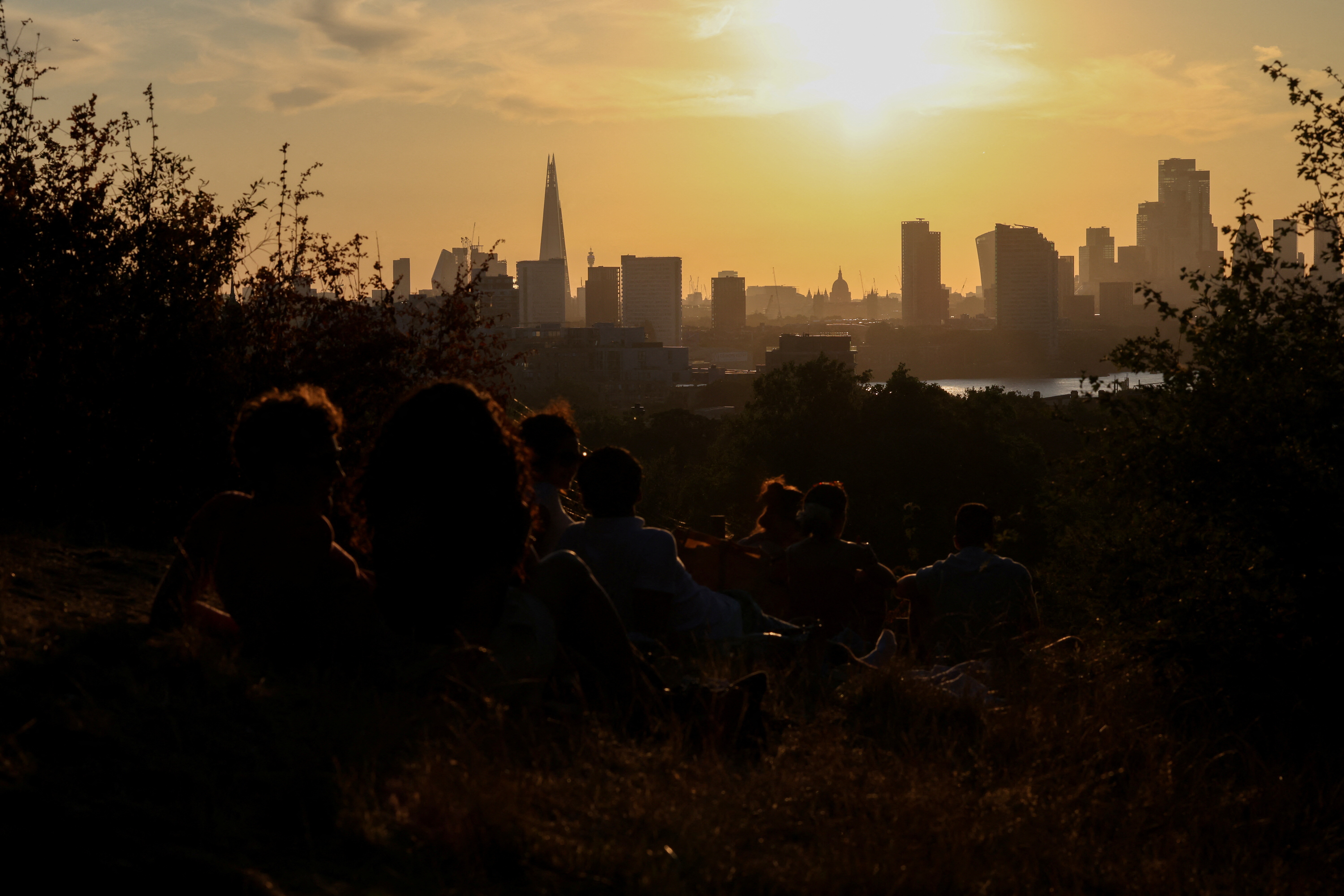 People watch the sunset over the city from Greenwhich Park, as the UK deals with its third heatwave of the year, in London, Britain, July 12, 2025.  REUTERS/Kevin Coombs