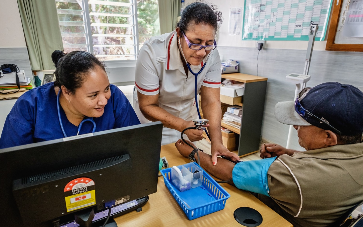 Two female medical staff take a patient's blood pressure.