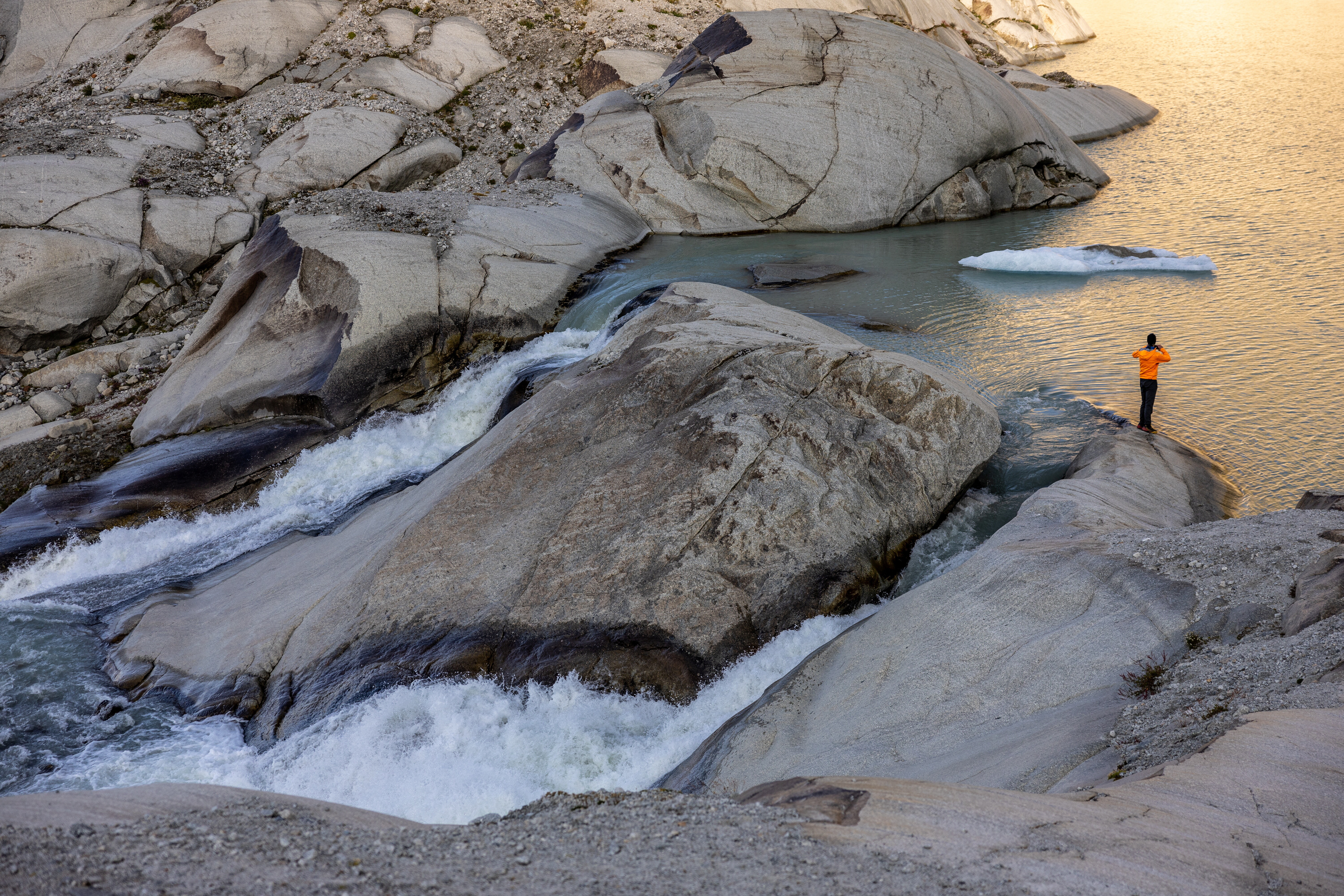 Glaciologist at ETHZ and head of the Glacier Monitoring in Switzerland (GLAMOS) Matthias Huss takes a picture as water flows down the valley at the source of the Rhone and its glacier amid climate change in Obergoms, Switzerland, August 27, 2024: Osmotic energy is a carbon-free renewable source with global potential
