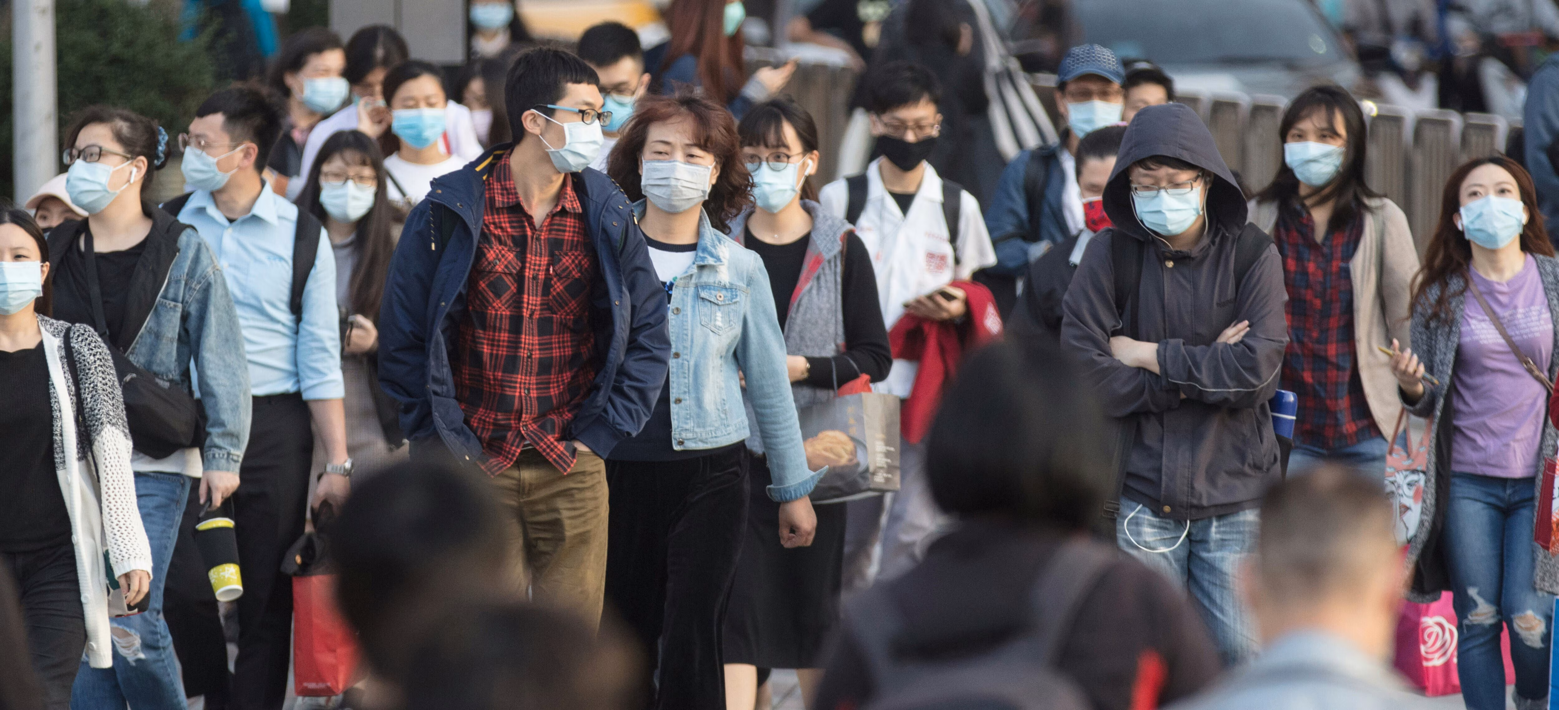 Personas cruzan una calle muy transitada con mascarilla; contaminación atmosférica.