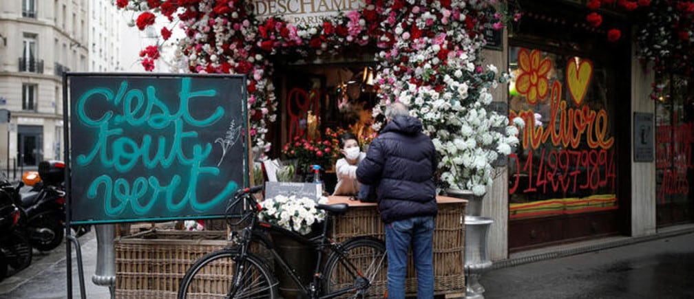 A customer buys some Lily of the Valley flowers, the symbol of Labour Day, from Deschamps flower shop in Paris, following the outbreak of the coronavirus disease (COVID-19), Paris, France, May 1, 2020. REUTERS/Benoit Tessier