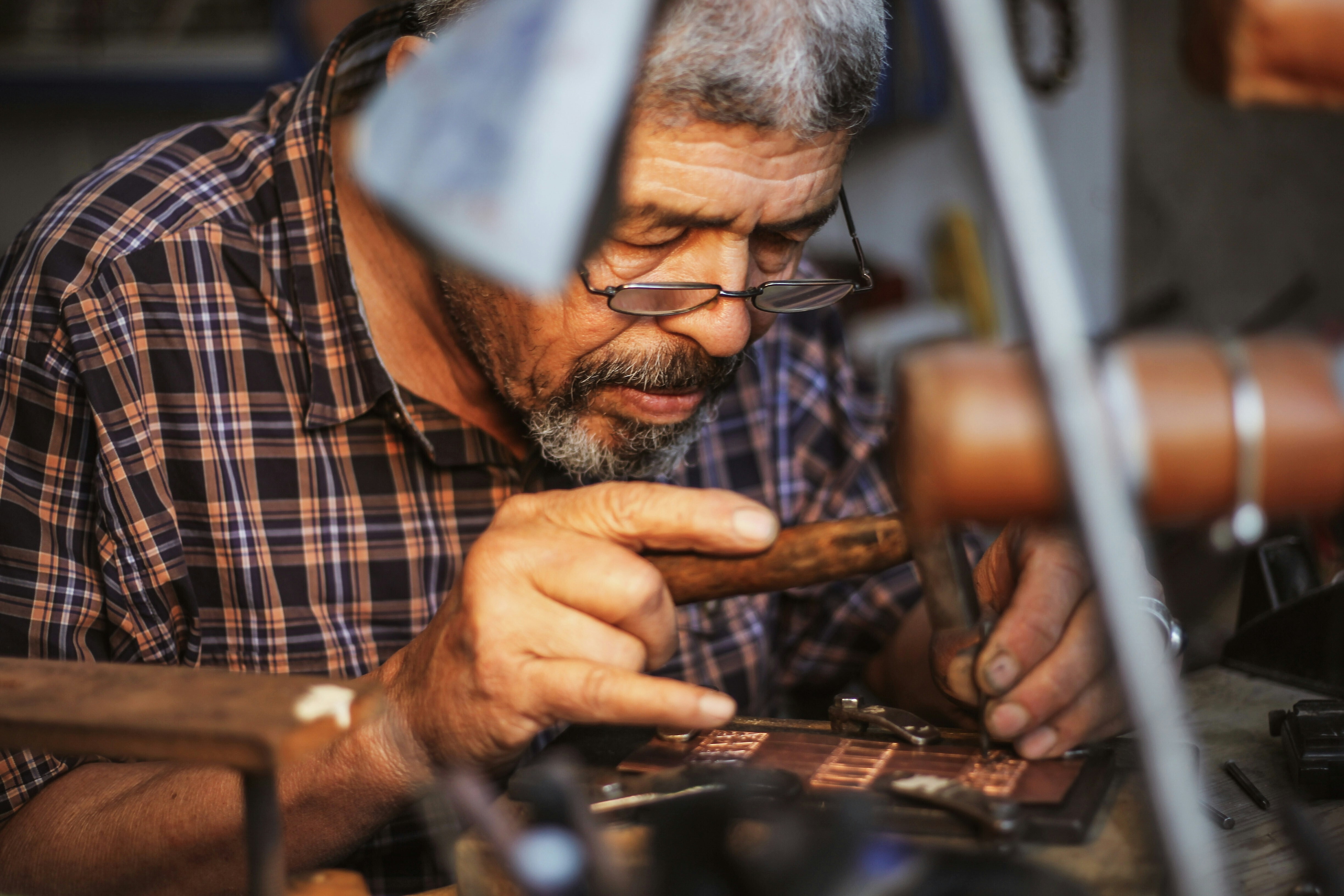 An older man with glasses works on an intricate task; eye health