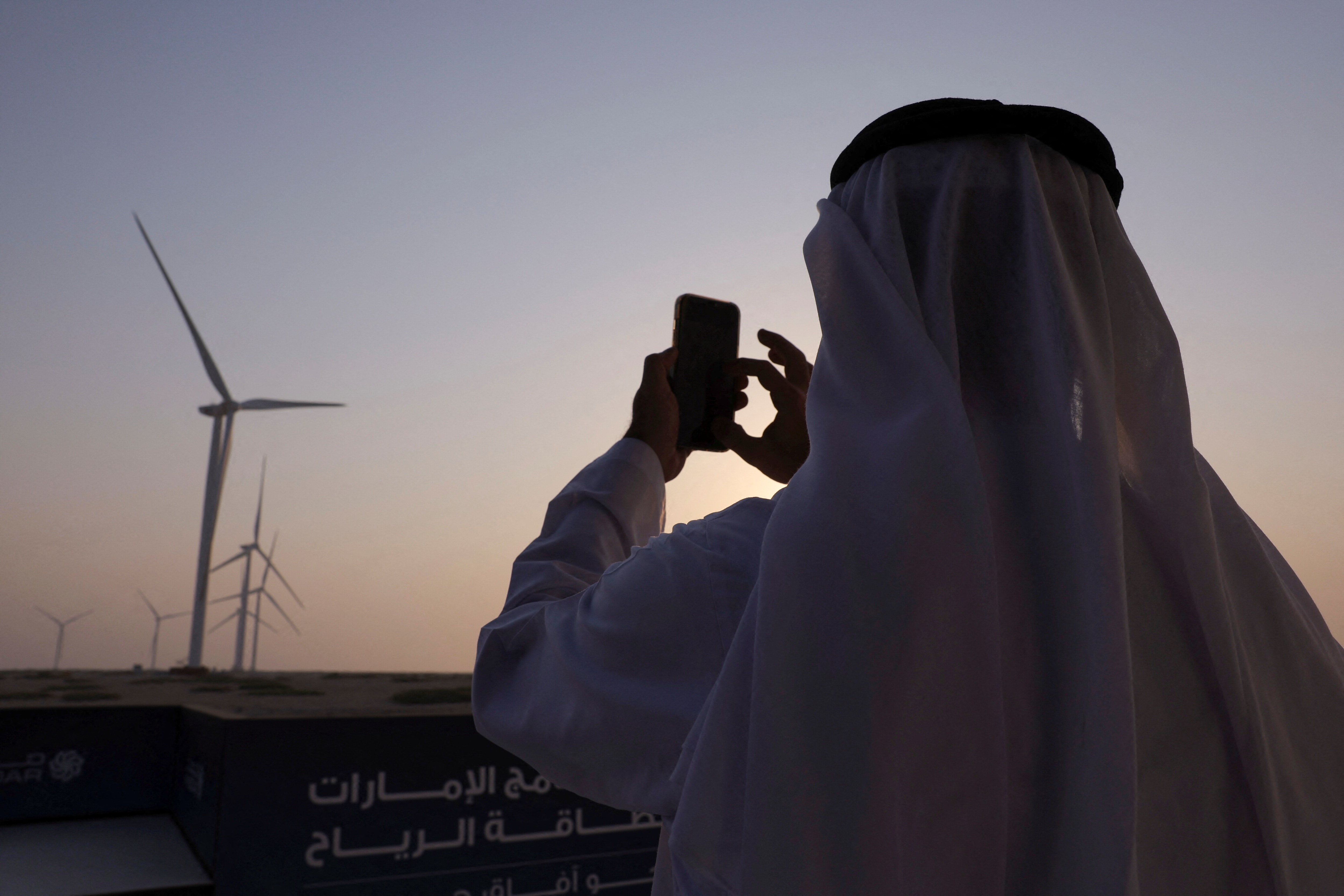 A person takes a picture of windmill turbines in Masdar's wind farm on Sir Bani Yas Island, in Abu Dhabi, United Arab Emirates, September 28, 2023: AI is a powerful enabler across the value chain of sustainable energy