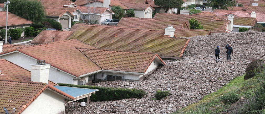  A TV news crew files a report behind damaged homes after a mud slide overtook at least 18 homes during heavy rains in Camarillo Springs, California December 12, 2014. A major storm pummeled California and the Pacific Northwest with heavy rain and high winds on Thursday, killing one man, knocking out power to tens of thousands of homes, disrupting flights and prompting schools to close. 