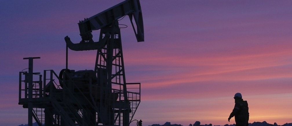 A worker walks past a pump jack on an oil field owned by Bashneft company near the village of Nikolo-Berezovka, northwest from Ufa, Bashkortostan, January 28, 2015. New European Union sanctions against Russia could include further capital markets restrictions, making it harder for Russian companies to refinance themselves and possibly affecting Russian sovereign bonds and access to advanced technology for the oil and gas sectors, EU officials said on Wednesday.