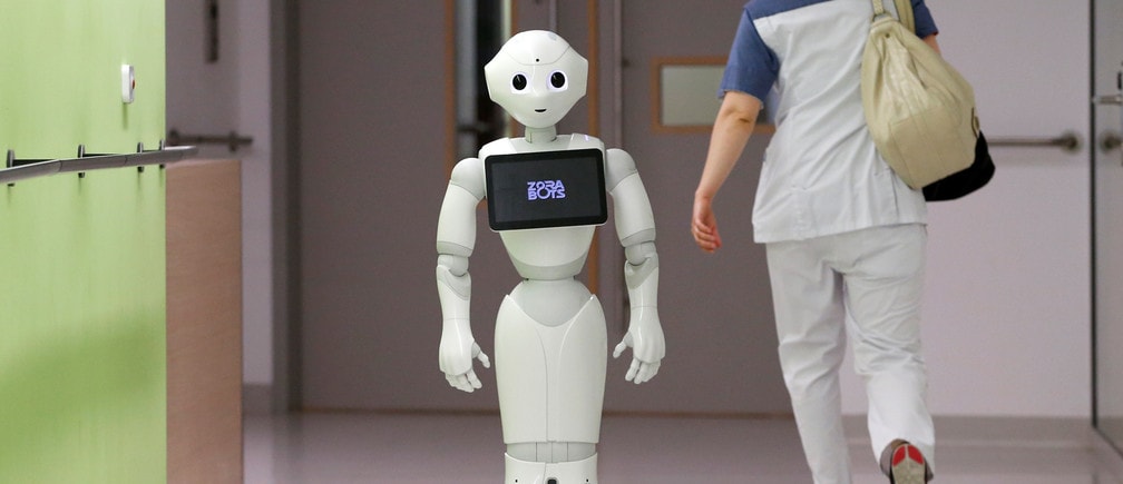 A nurse walks by new recruit "Pepper" the robot, a humanoid robot designed to welcome and take care of visitors and patients, at AZ Damiaan hospital in Ostend, Belgium June 16, 2016. REUTERS/Francois Lenoir - D1AETKGAYIAA