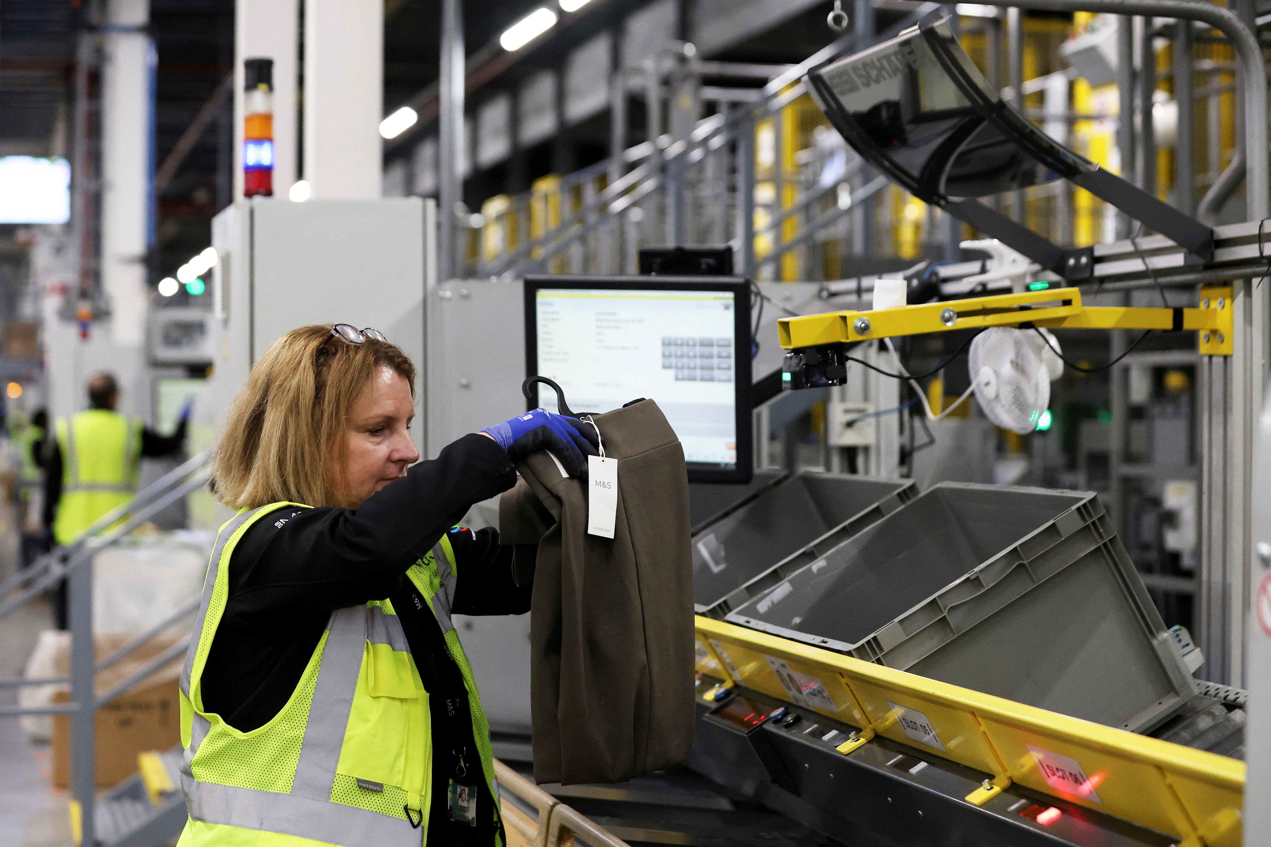 An employee inspects items of clothing on the automated sorting system at a Marks & Spencer (M&S) distribution centre in Castle Donington, Leicestershire, Britain, November 7, 2025. REUTERS/Temilade Adelaja