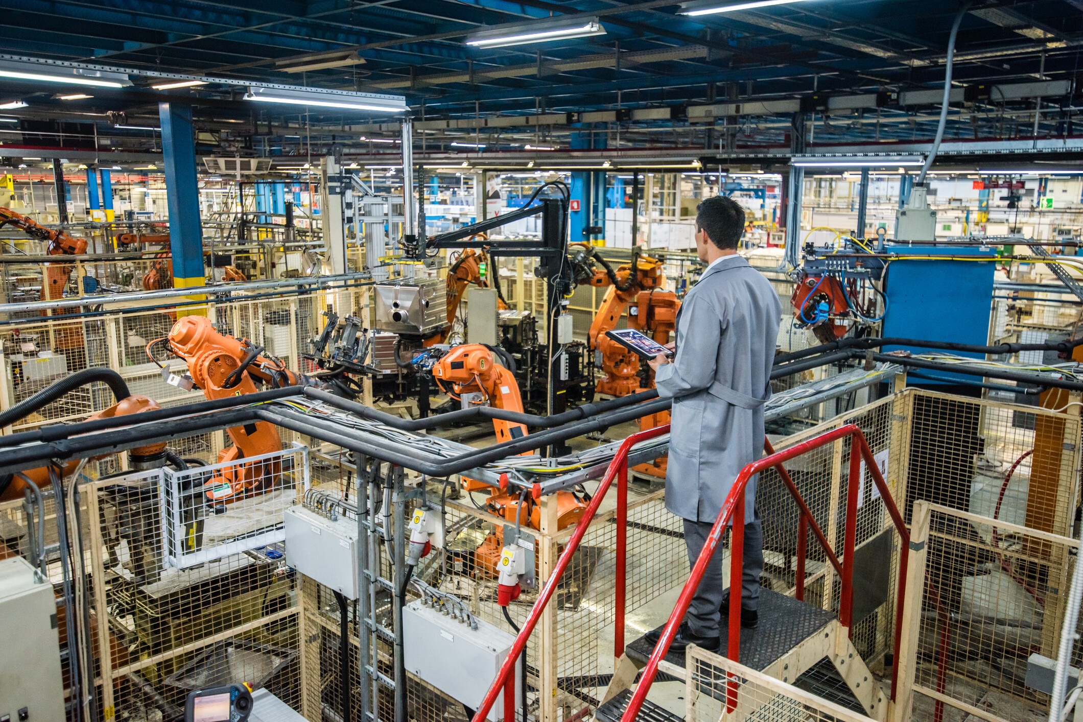 Male factory engineer inspecting the work process of the robots performing their operations in appliance manufacturing factory. Autonomous AI
