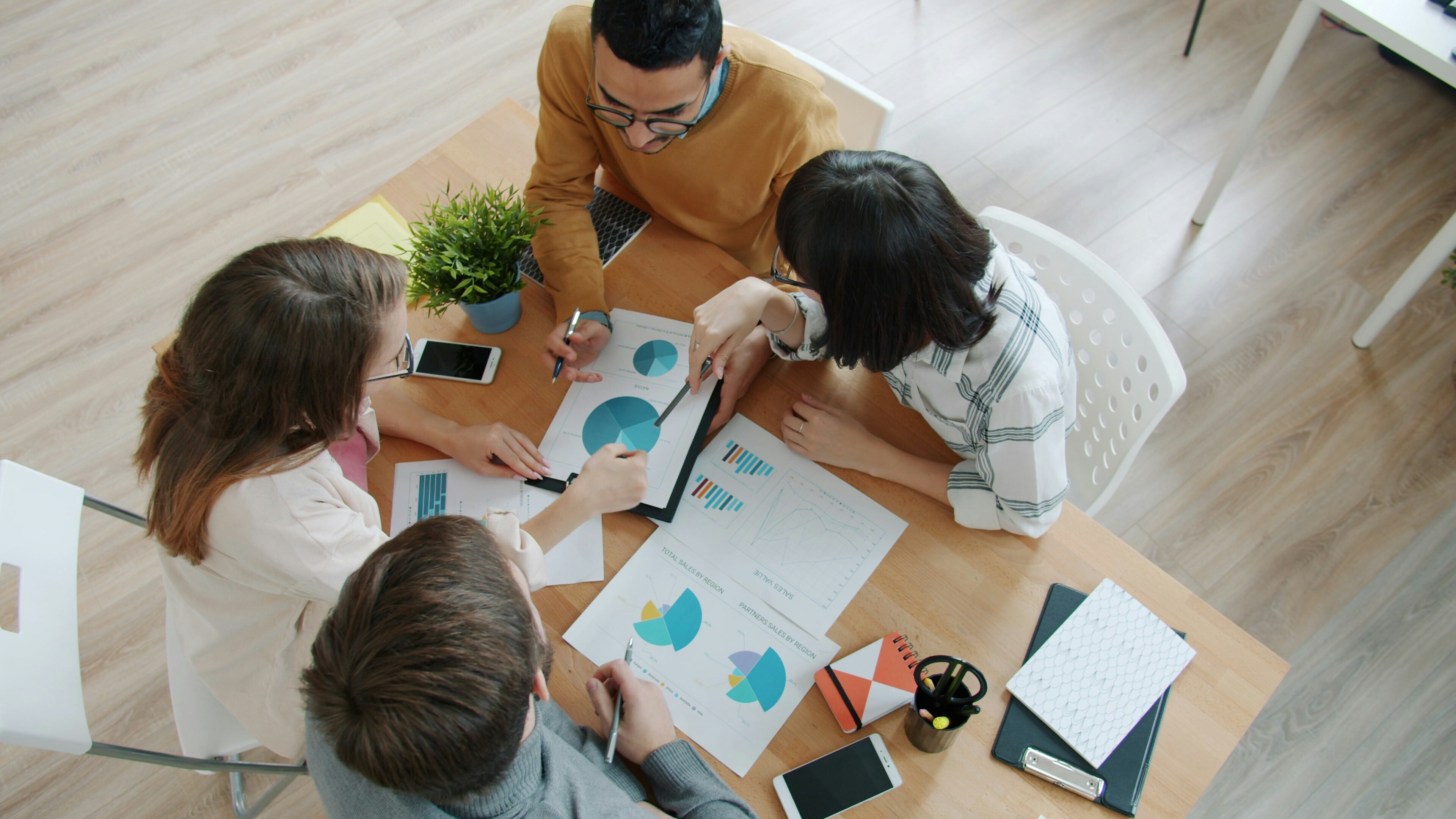 A group of colleagues discuss a report, data charts; AI tools, search engines, research data.