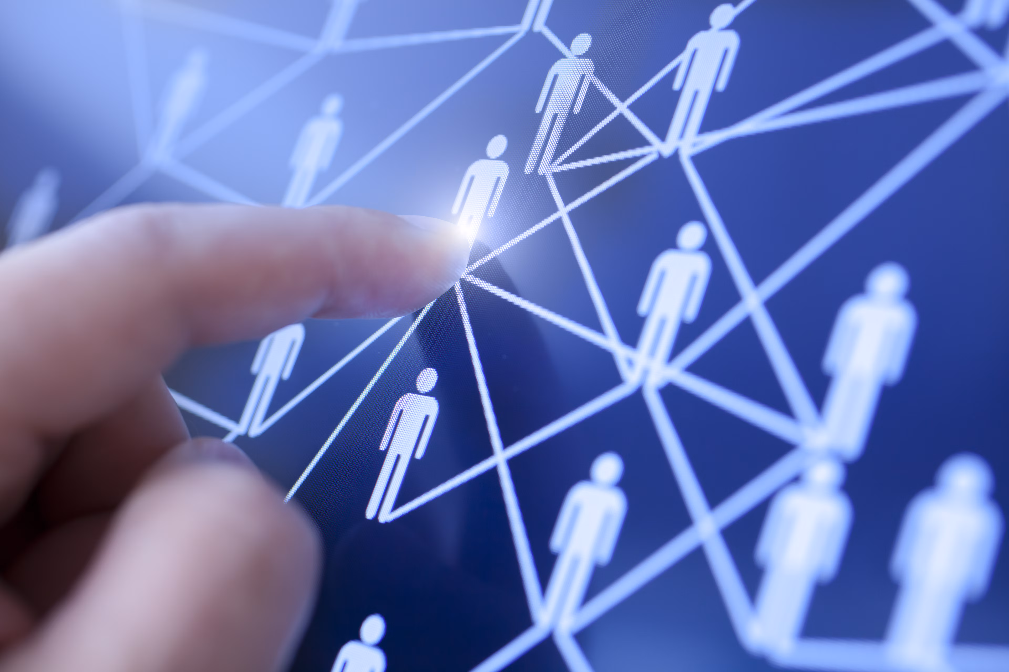 Una mano humana tocando una pantalla táctil con personas conectadas en red: Los jefes de recursos humanos deben fomentar la perspicacia empresarial de los empleados porque esto refuerza el rendimiento individual.