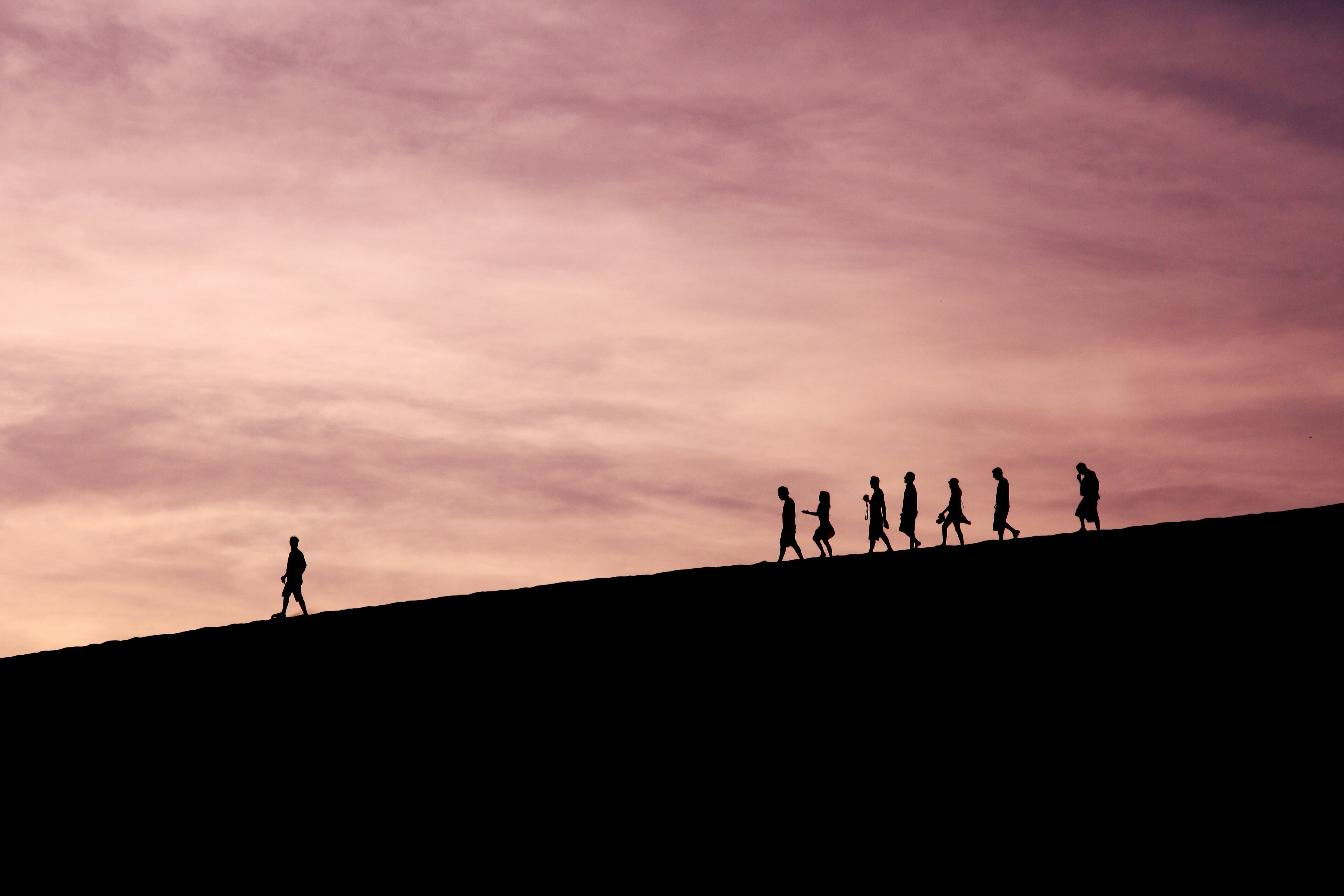 A silhouette of people marching down a hill with one person ahead: Dialogue and collaboration are essential leadership tools in the new world