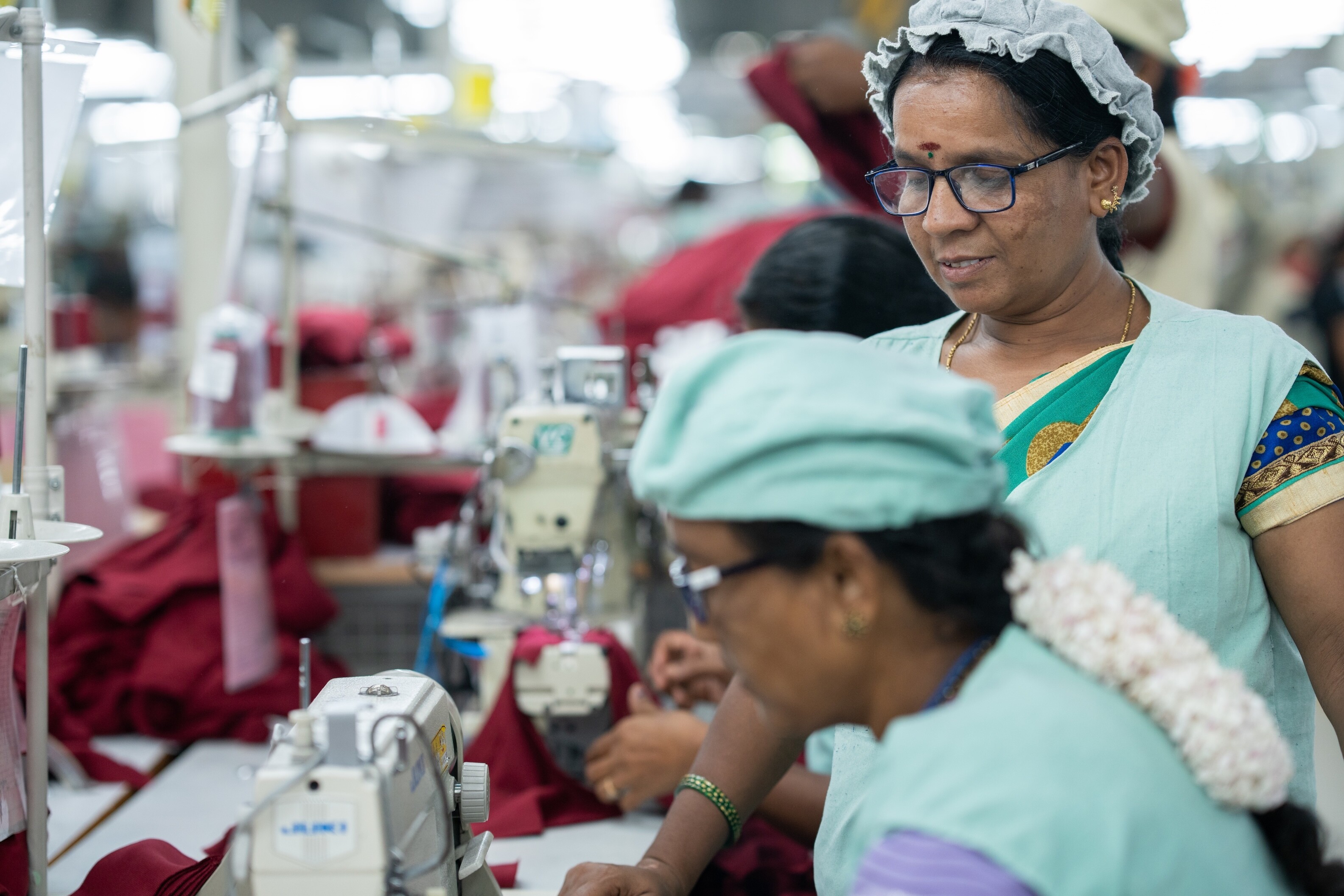 Factory workers in India are seen working at sewing machines.