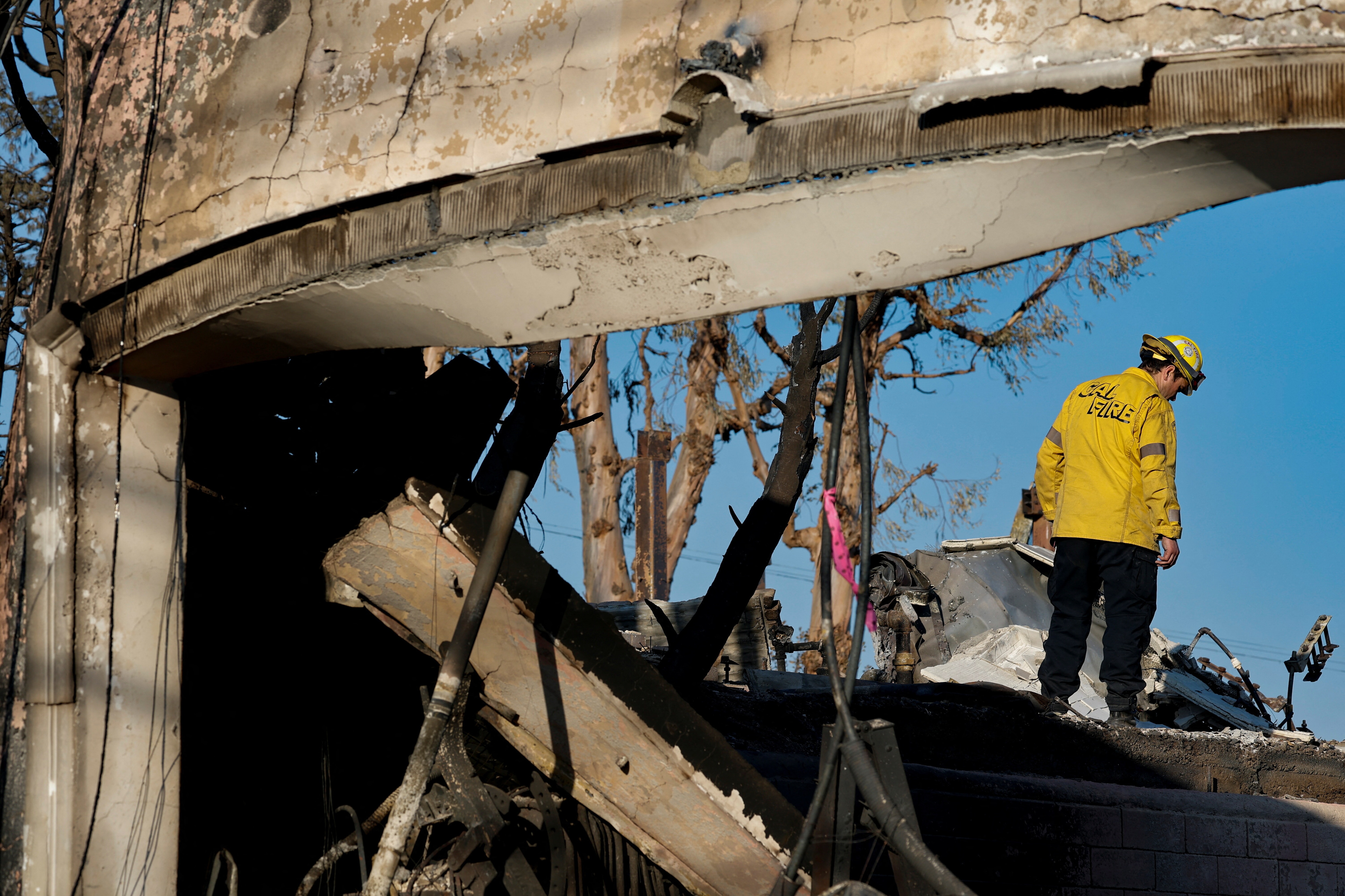 A firefighter surveys the remains of a home destroyed by fire, illustrating the increasing disaster risk and the need for resilient infrastructure.