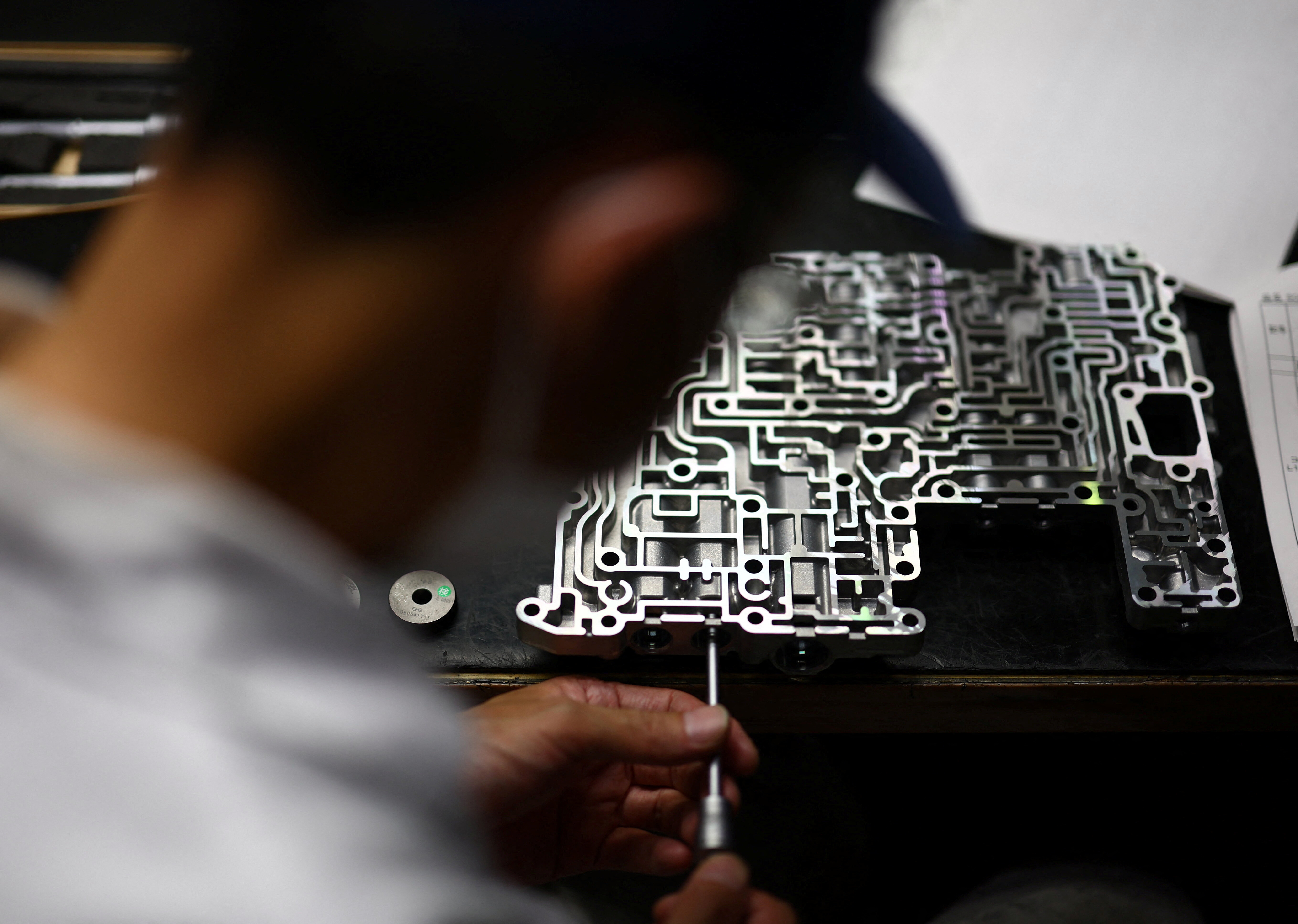 A man conducts a quality inspection for automobile transmission parts inside a factory at Kyowa Industrial Co. in Takasaki, Gunma Prefecture, Japan April 11, 2025.  REUTERS/Issei Kato