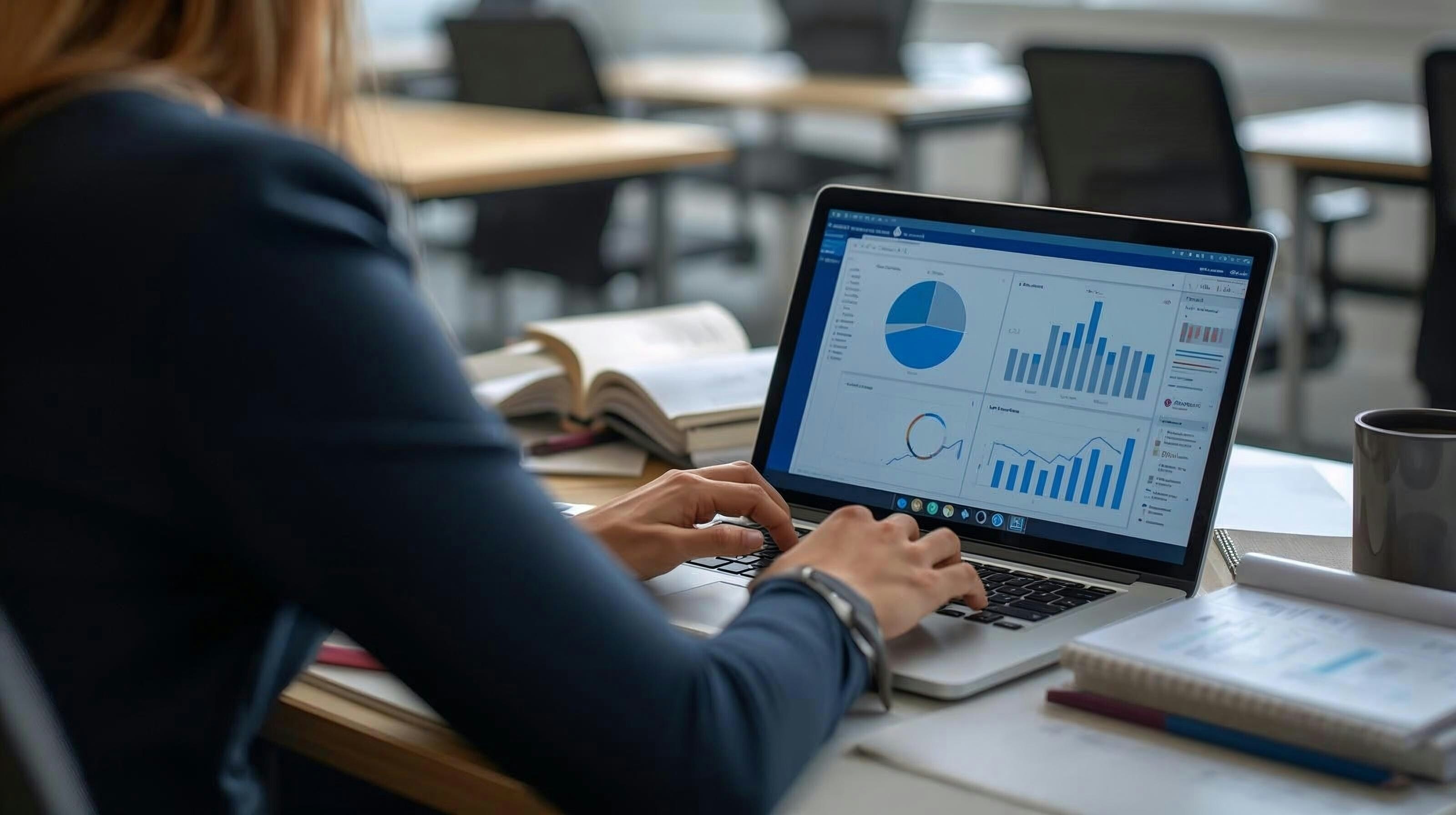 Someone types at a computer showing pie charts and graphs.