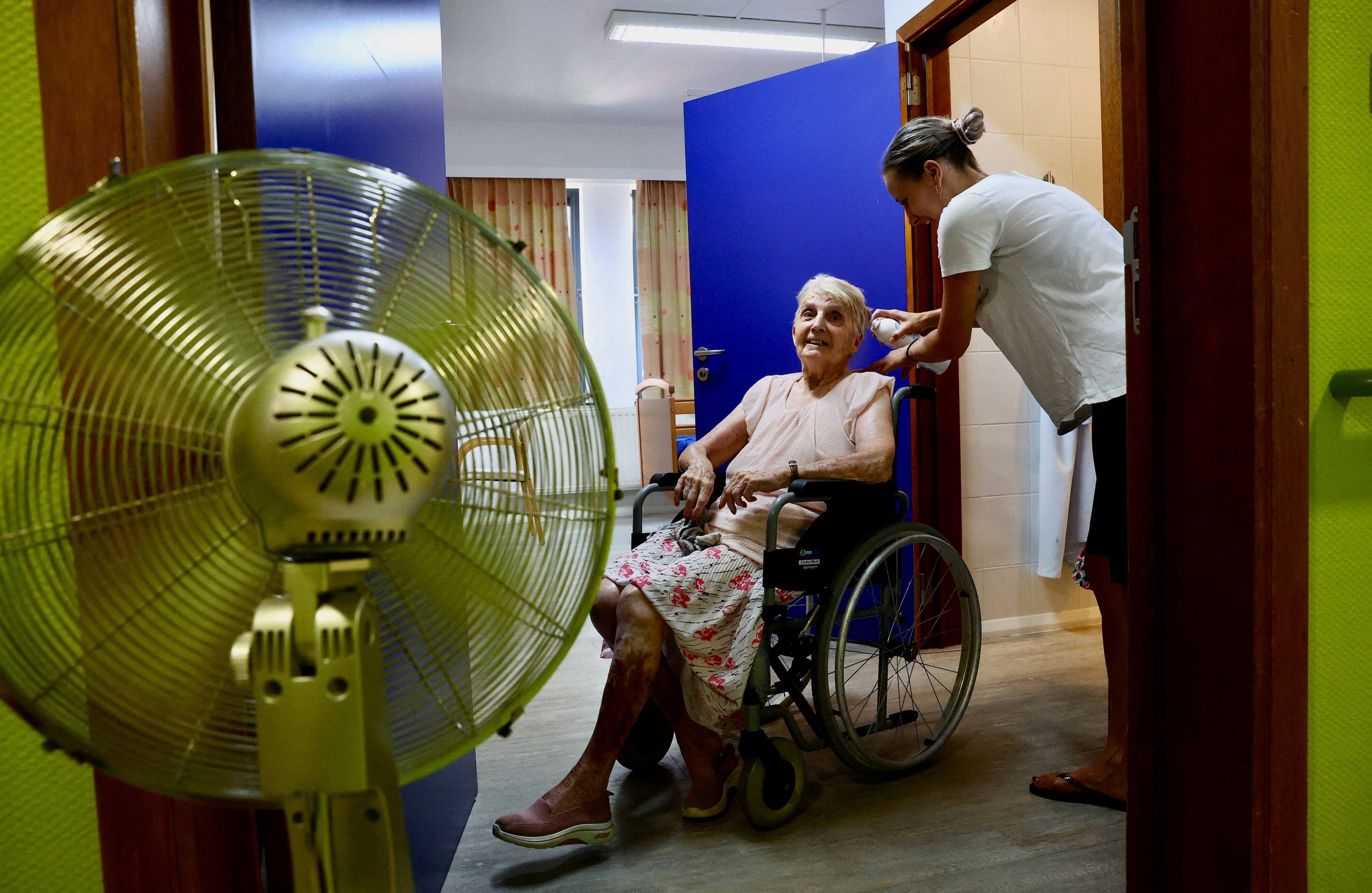 A resident at the house for elderly persons, La Maison de Chatelet, is refreshed by a staff member with a mist moisturiser, as a heatwave hits Europe, in Chatelet, Belgium.