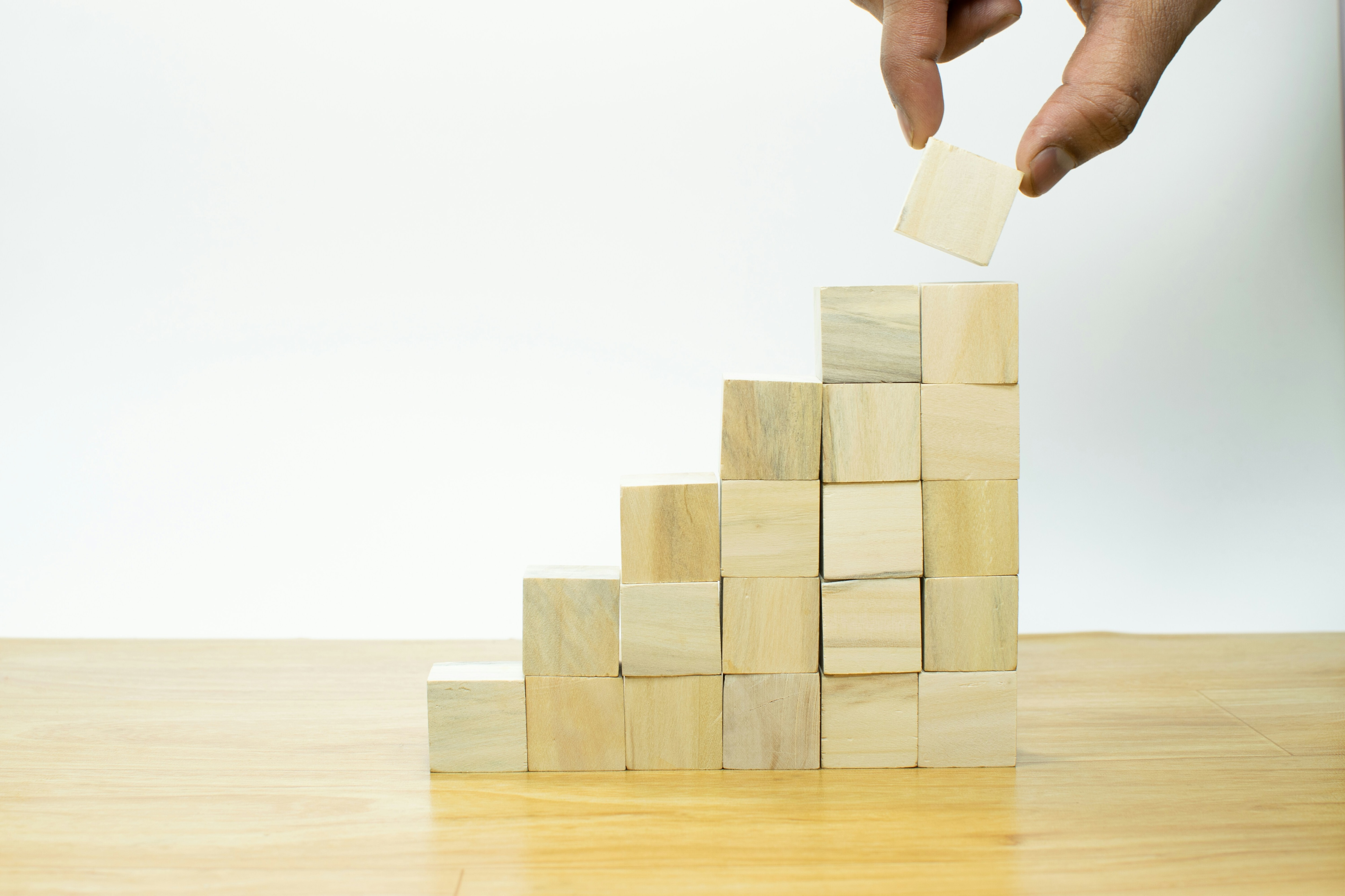 Sand coloured uilding blocks and a hand placing block: Leading organizations can unlock potential for industry as an AI-first enterprise
