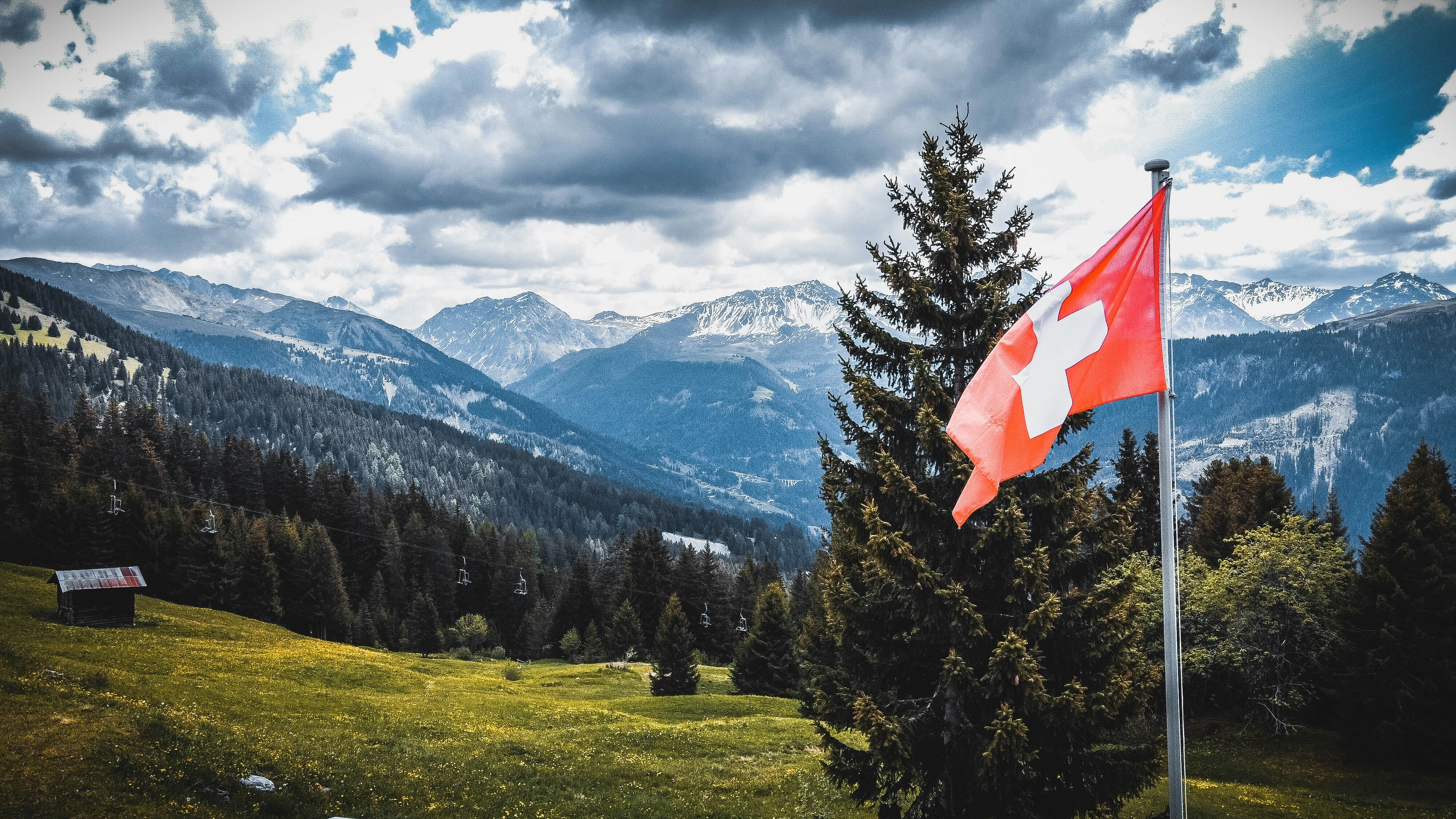Swiss mountain scene with Swiss flag in foreground.