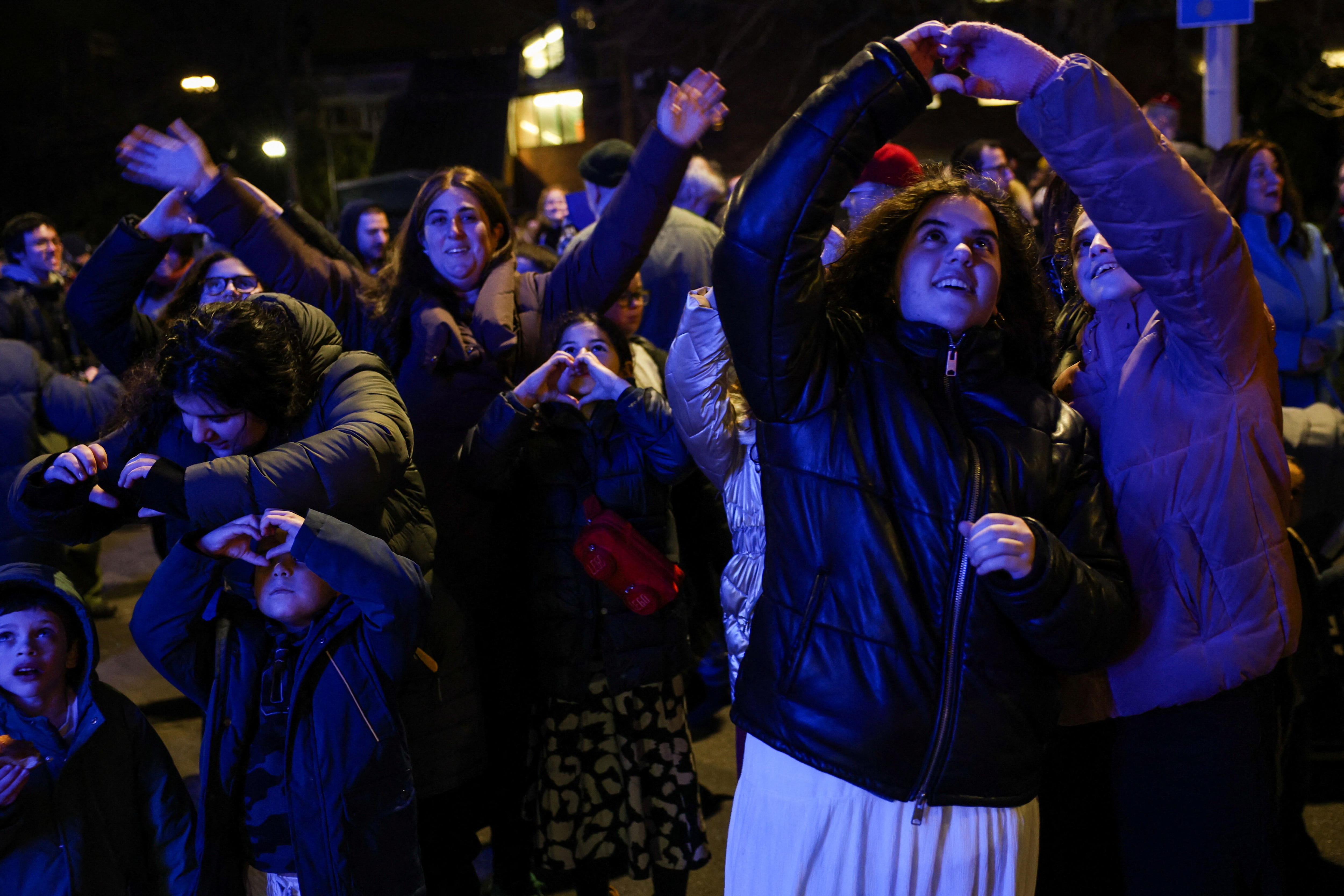 Youth make heart-shaped hand gestures during an event to light the Chabad Golders Green Station 30-foot Menorah on the first night of Hanukkah, in London, Britain, December 14, 2025. 