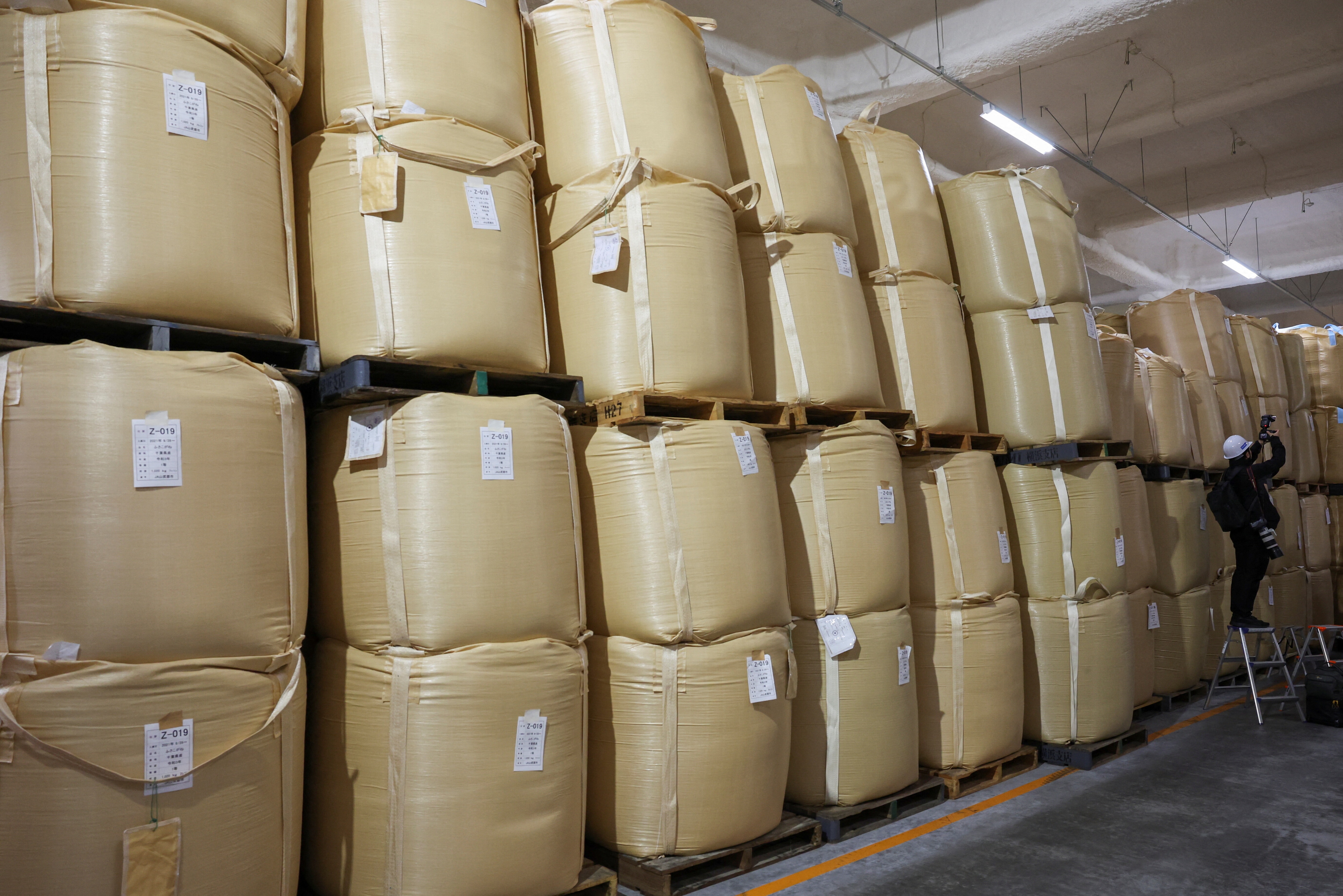 A photographer takes a photo of sacks of stockpiled rice at a warehouse in Kanagawa, Japan May 30, 2025. REUTERS/Kim Kyung-Hoon