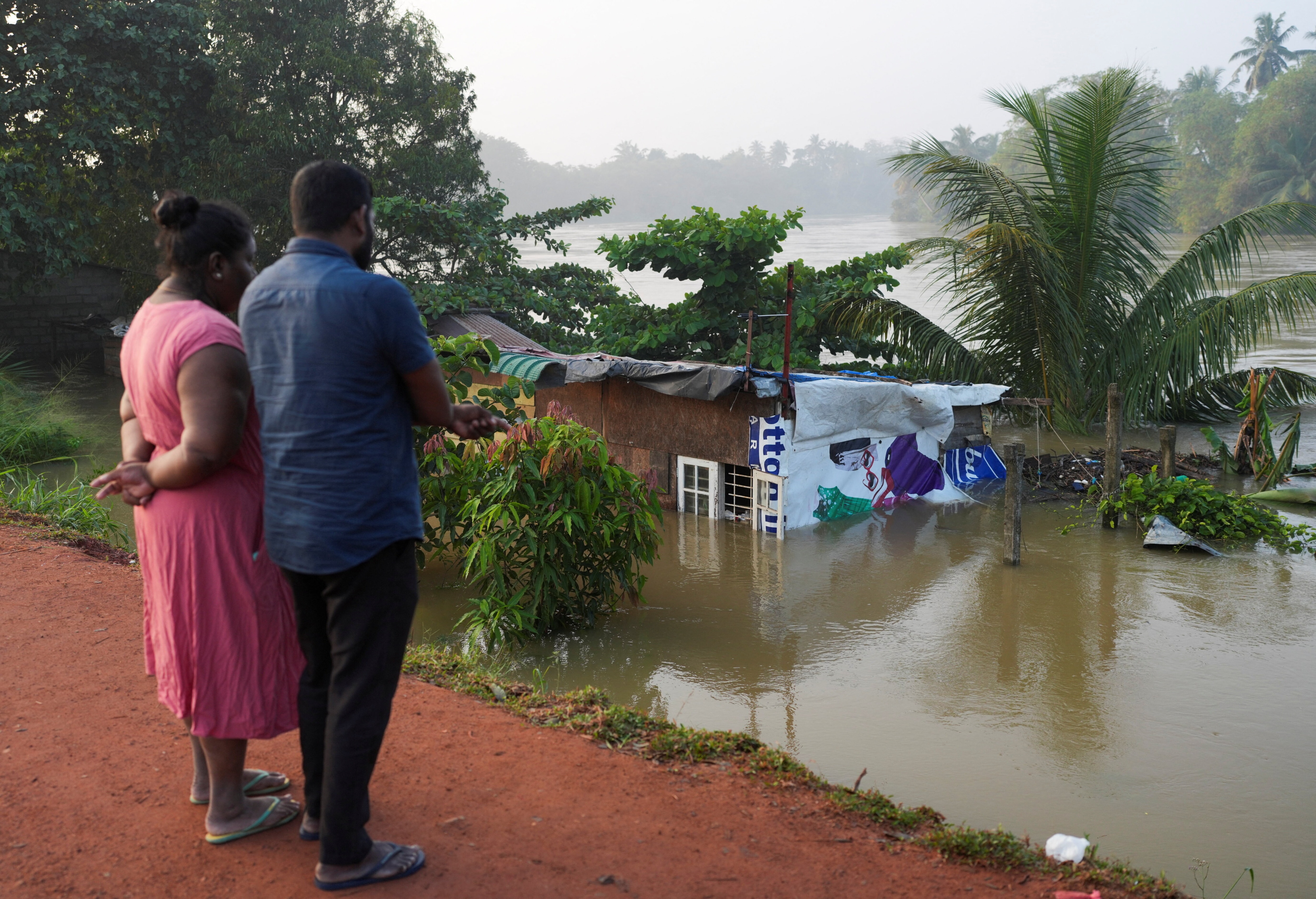People look towards a house partially submersed by the flood, following Cyclone Ditwah in Peliyagoda, Sri Lanka, December 1, 2025. Climate disasters like floods often come hand in hand with debt increases, exacerbating their impact.